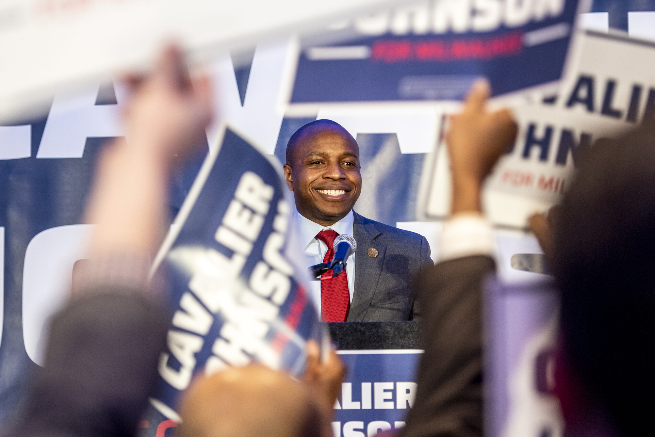 Cavalier Johnson smiles as his supporters hold up signs.