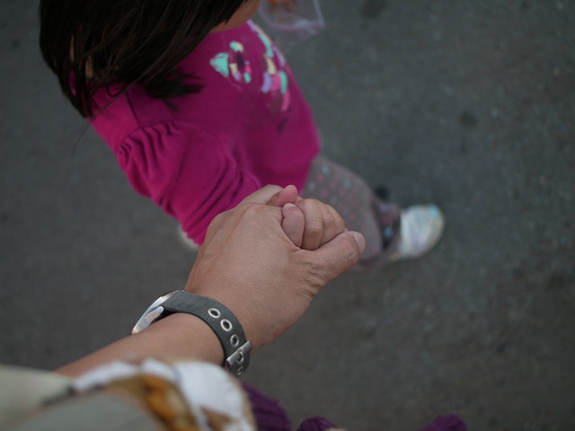 adult walking hand in hand with a young child