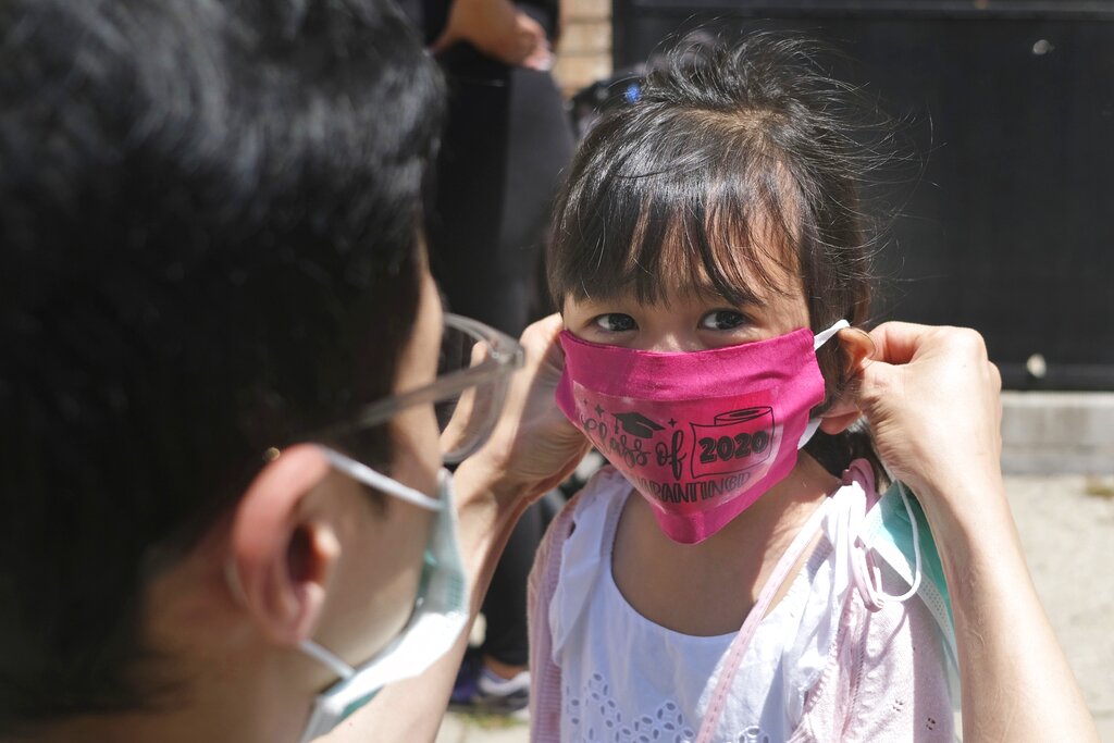 A parent placing a face mask on their child