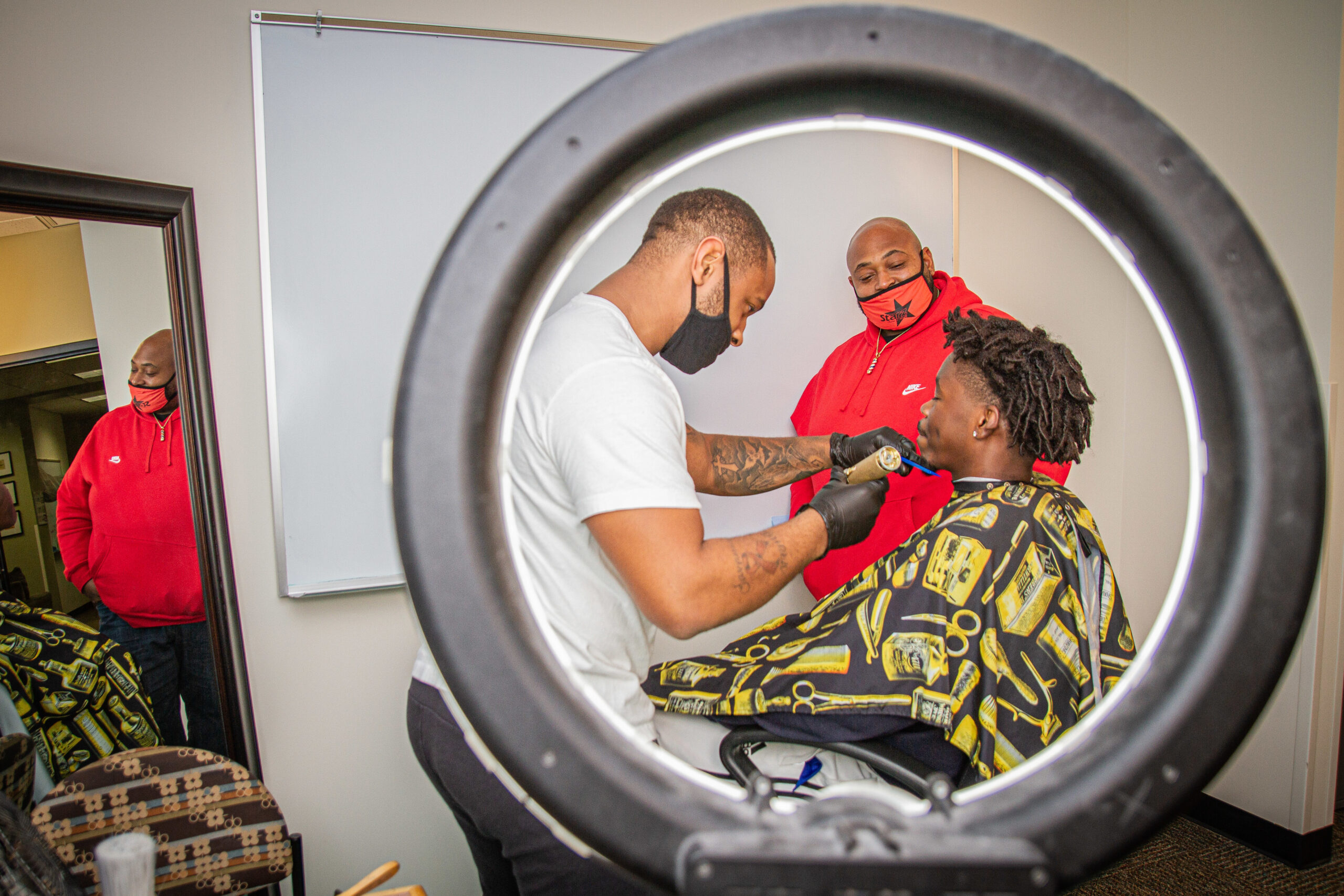 Chris Kimbrough watches his son cut the hair of a college student