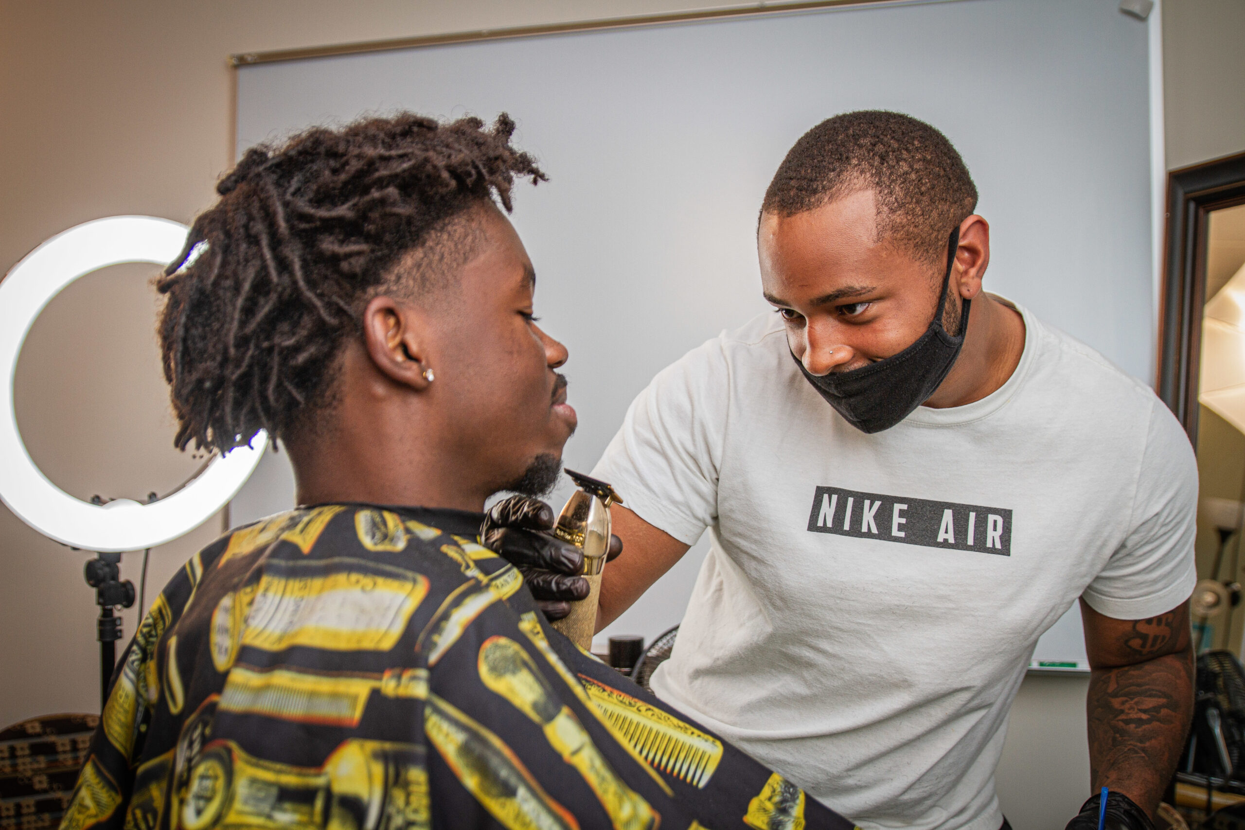 A man trims facial hair of a St. Norbert College student at a local barber shop