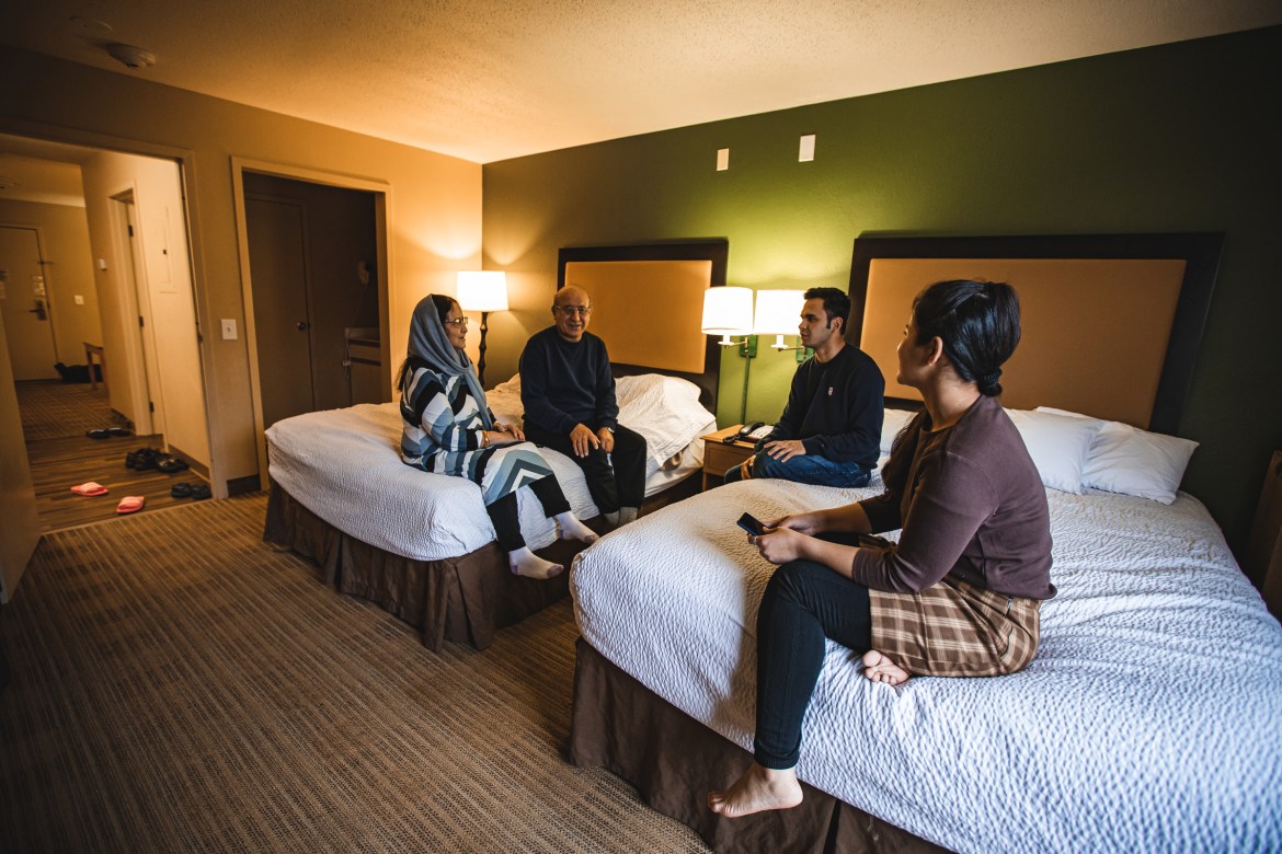 A family of four sits and talks on hotel beds