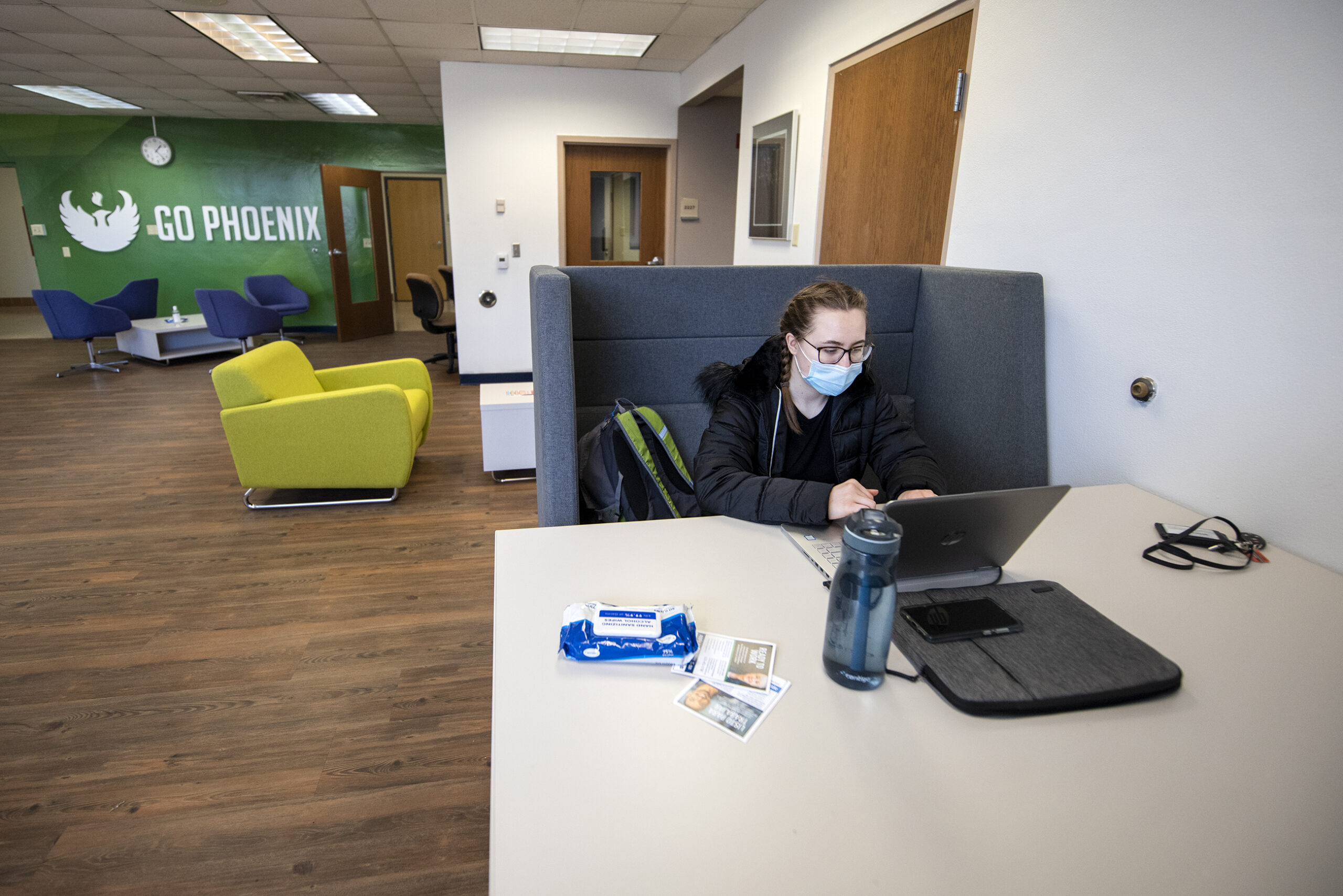 A student sits at a table with her laptop and other supplies.