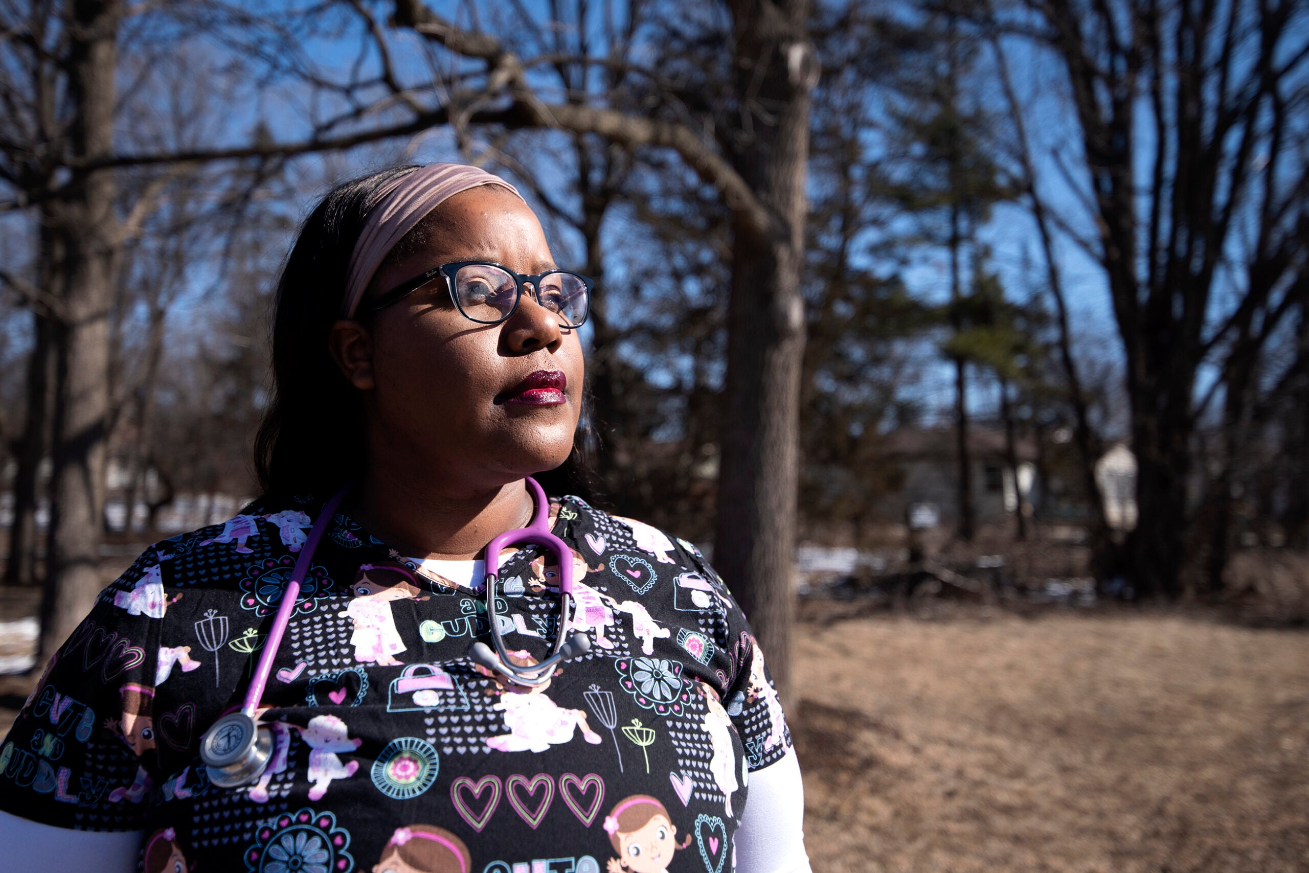 Sharmaria Russell wears scrubs and a stethoscope as she stands outside in the sunlight.