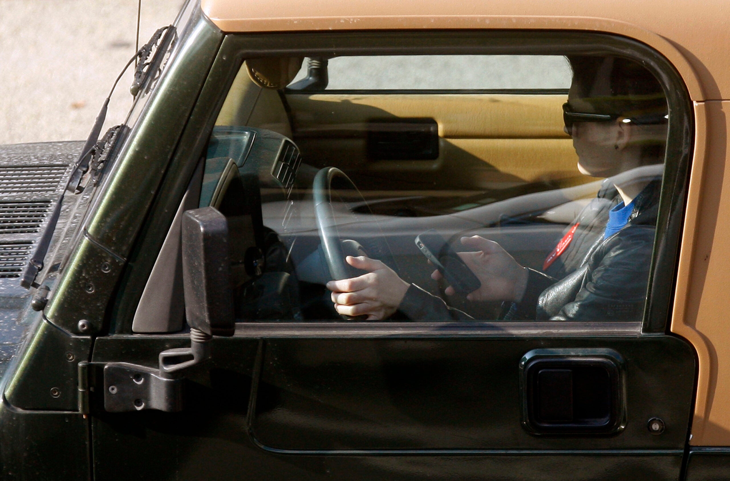 A teen driver uses an iPhone while driving in Los Angeles