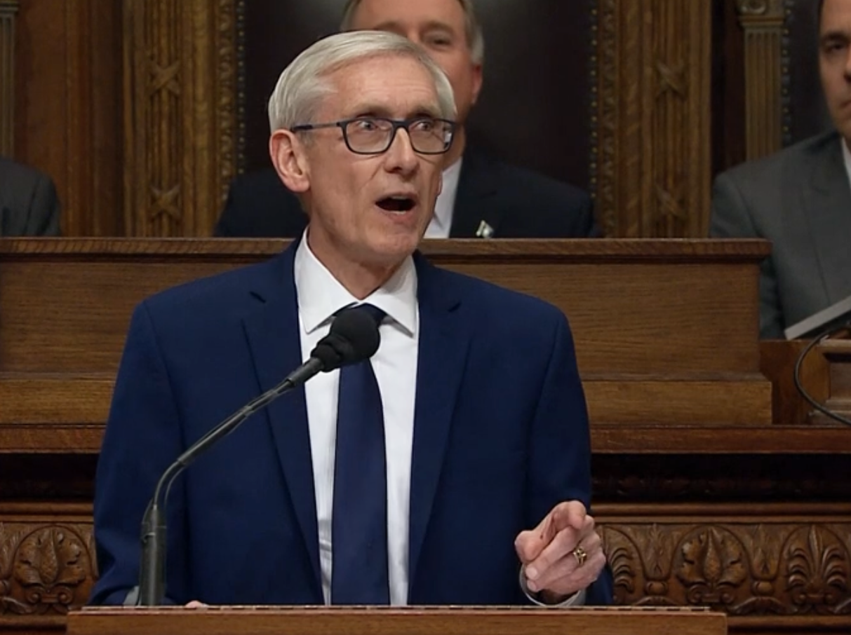 Tony Evers in a dark suit speaks at a podium
