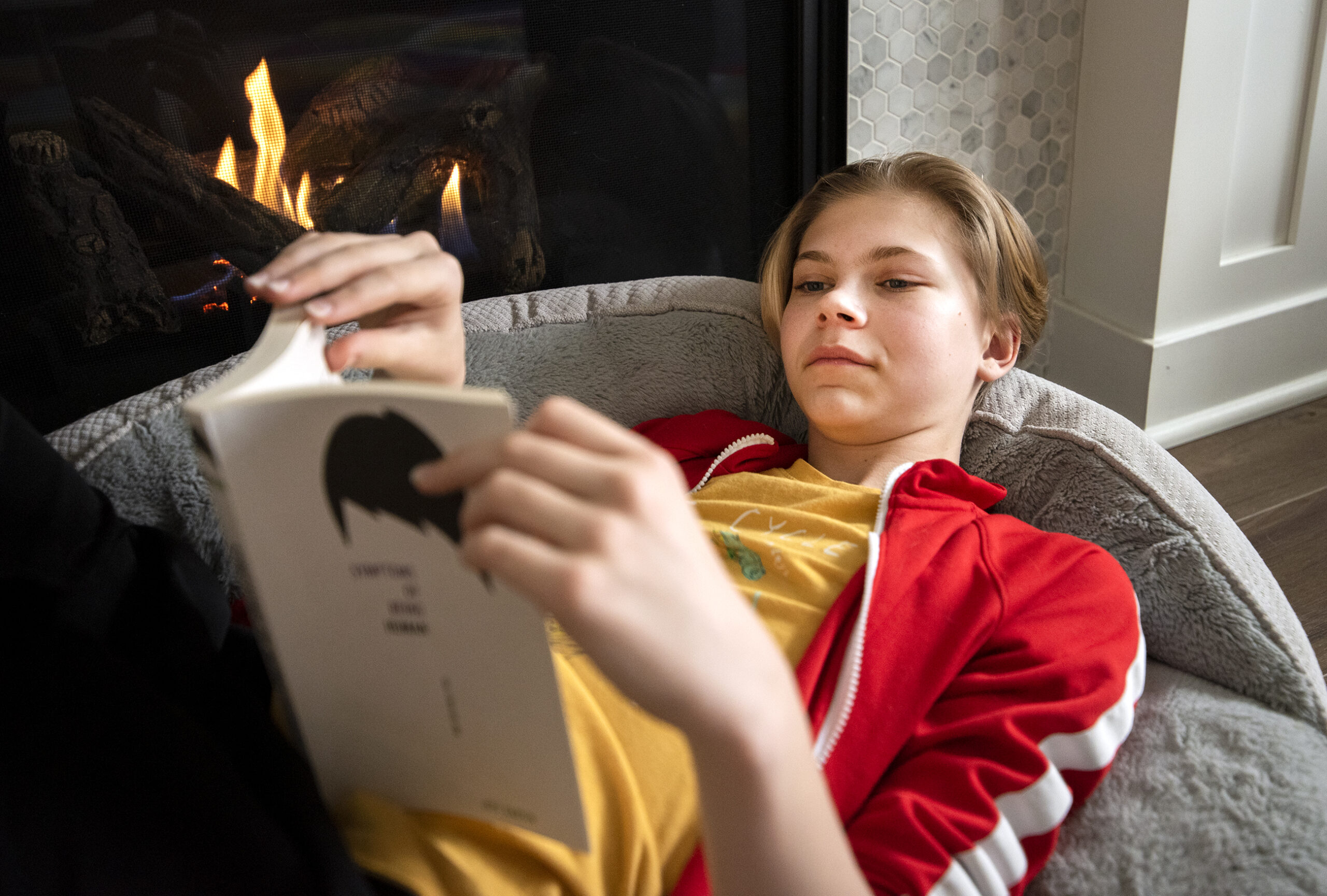 Bailey Mosling reads a book by the fireplace.