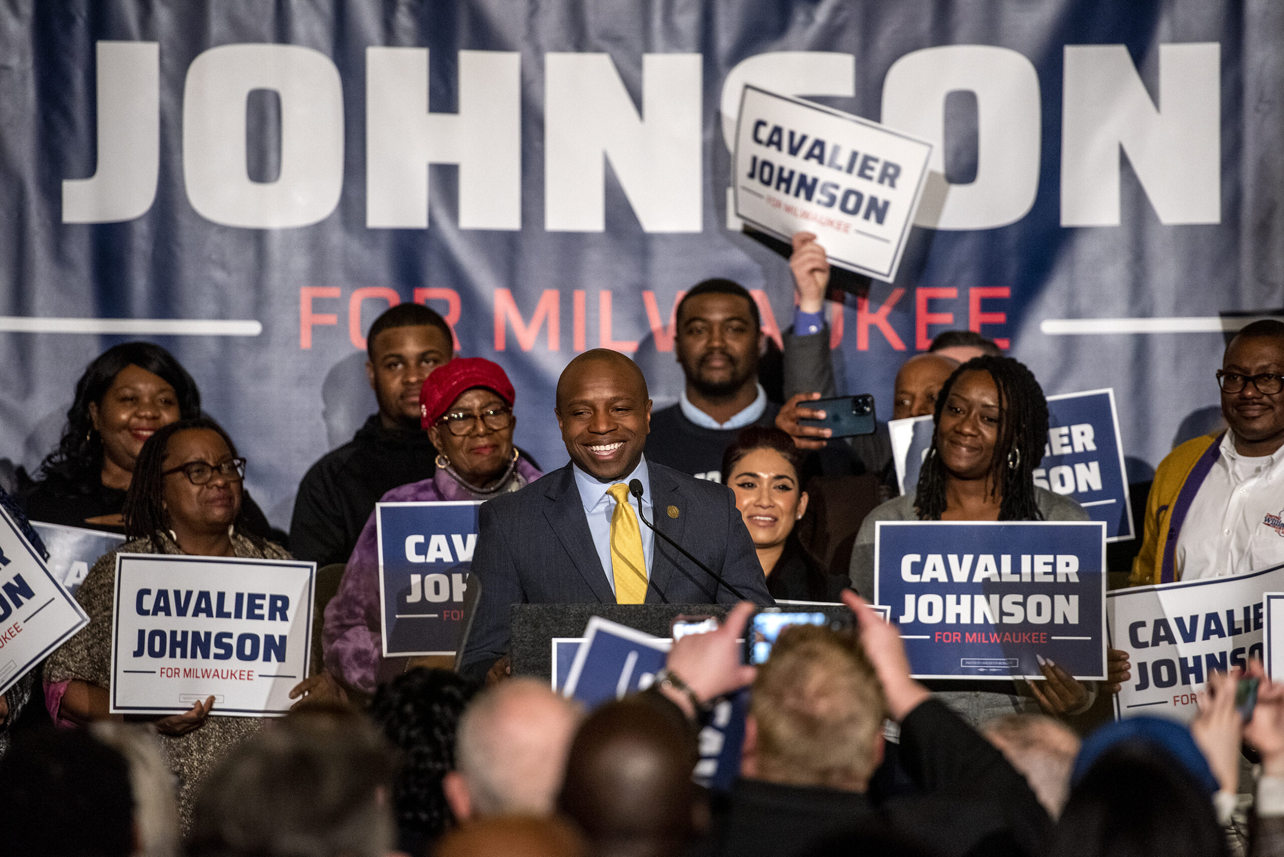 Supporters hold signs as Cavalier Johnson takes the stage.