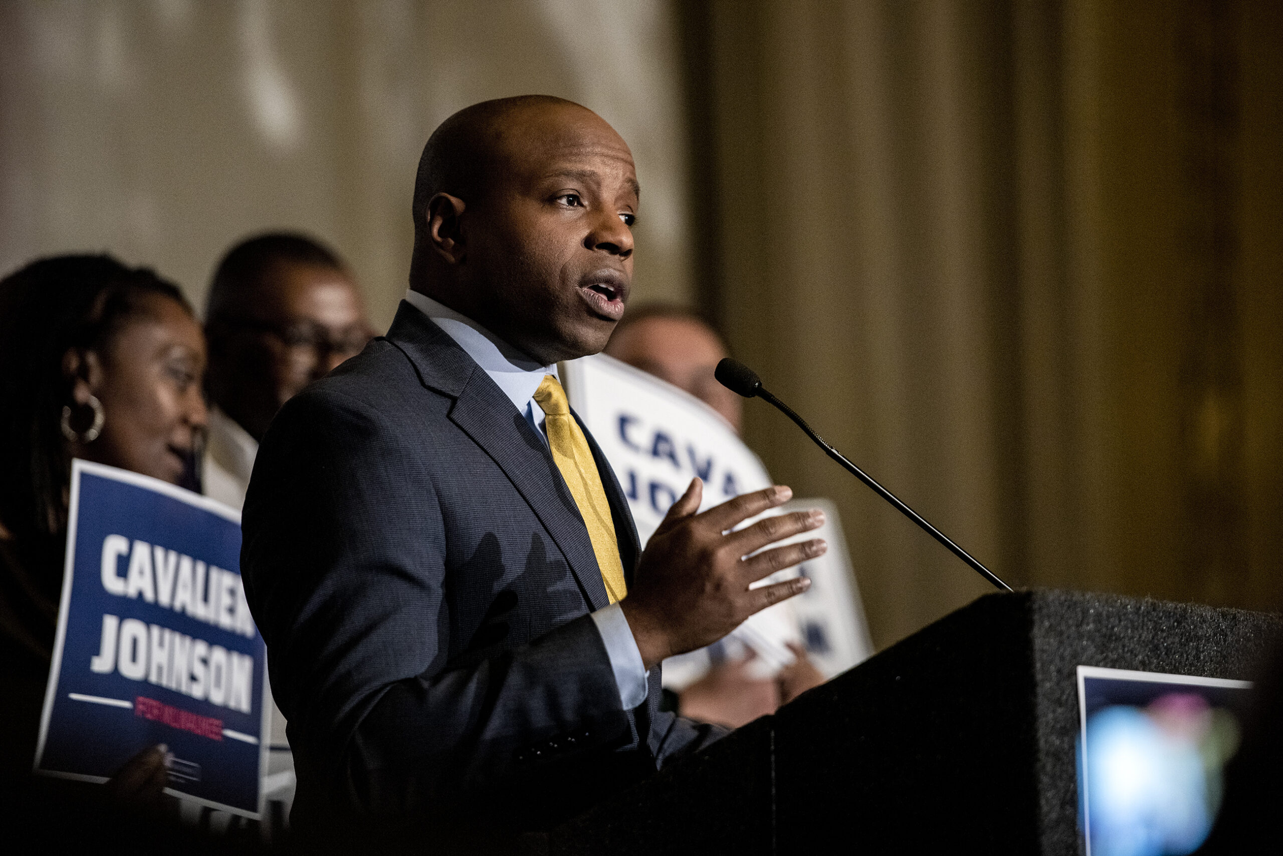 Cavalier Johnson gestures as he speaks at a podium.