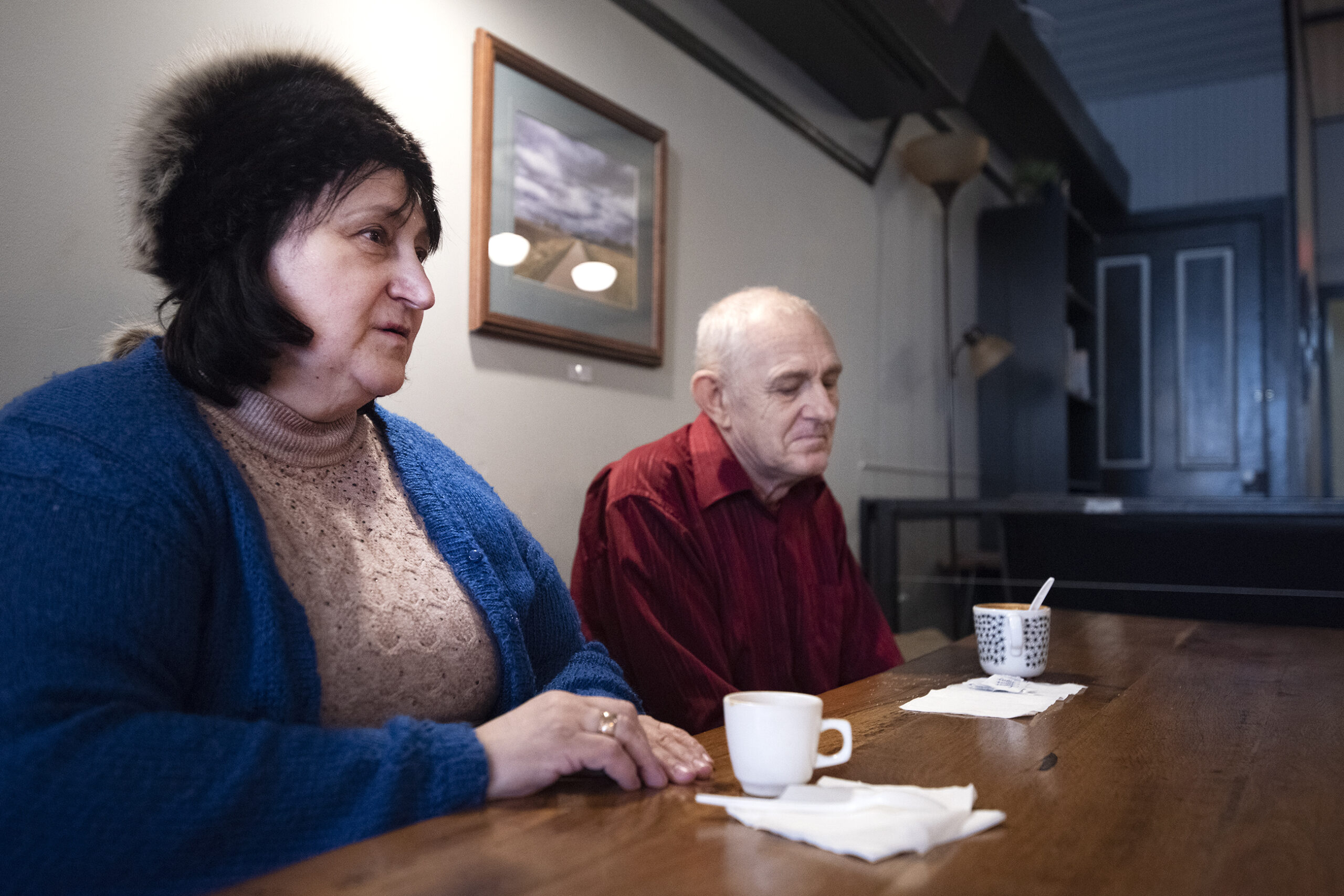Tanya and Slava sit at a table with coffee.
