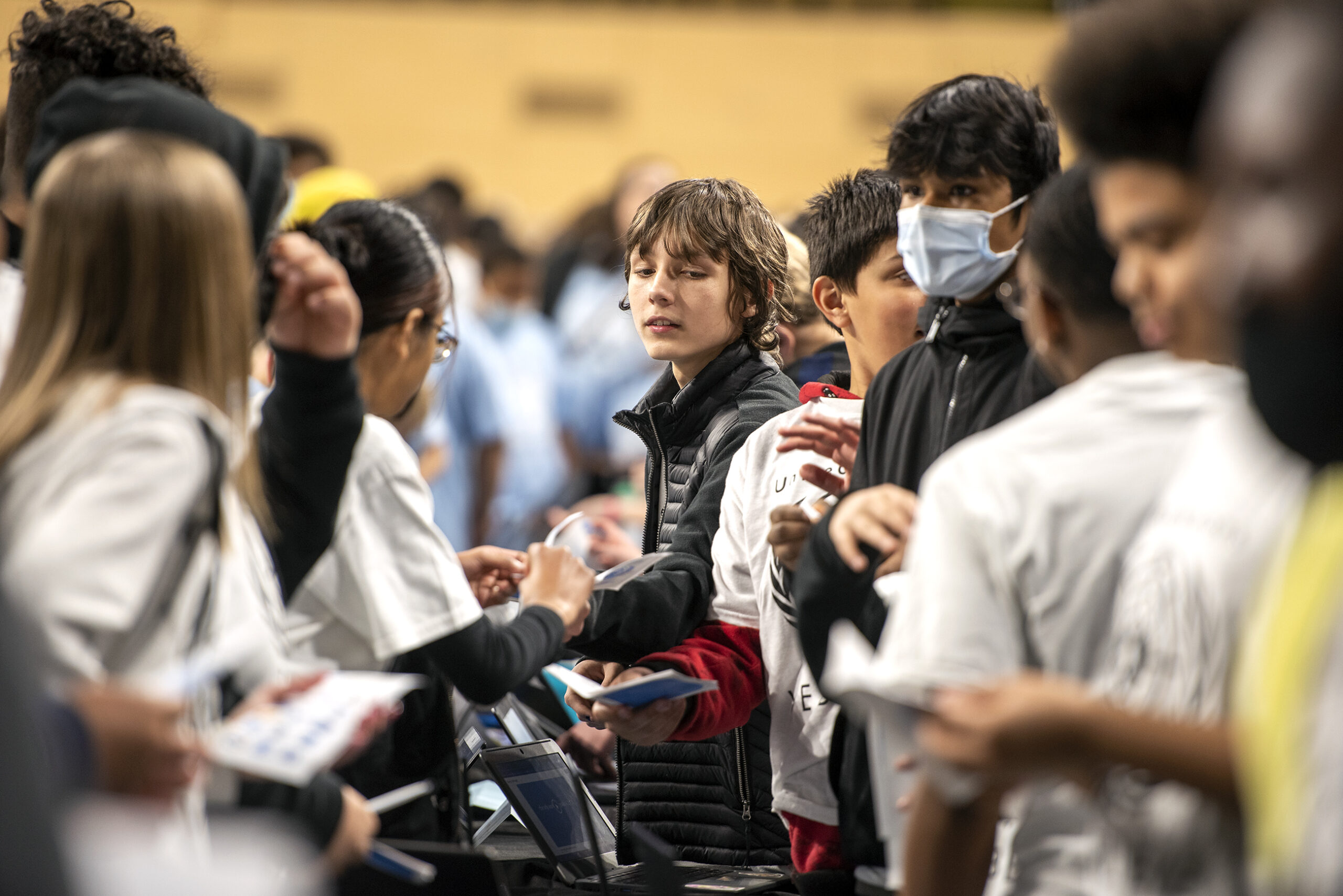 A student hands a passport to another student for a sticker.