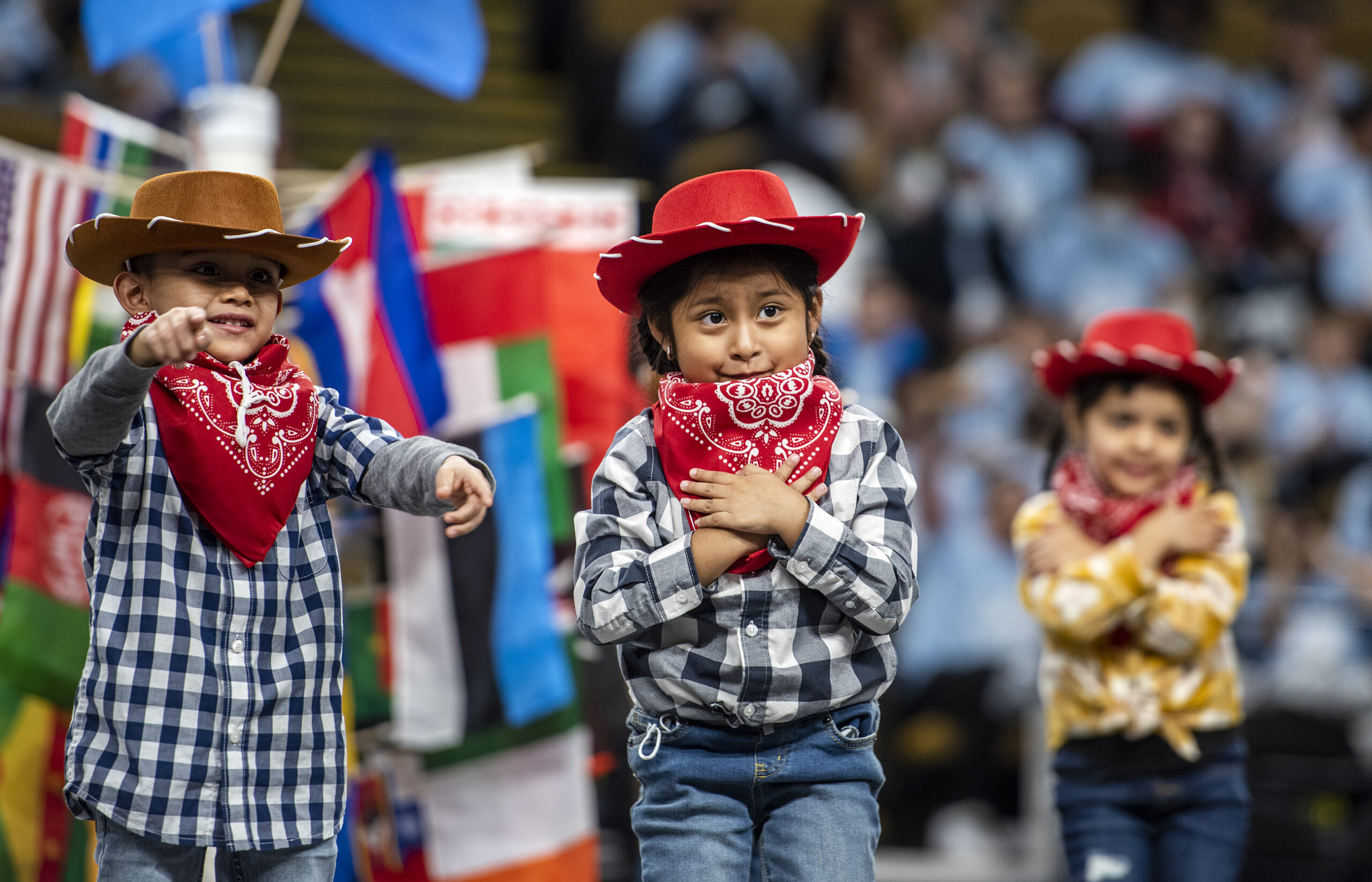 Three students in cowboy hats perform a dance on stage.