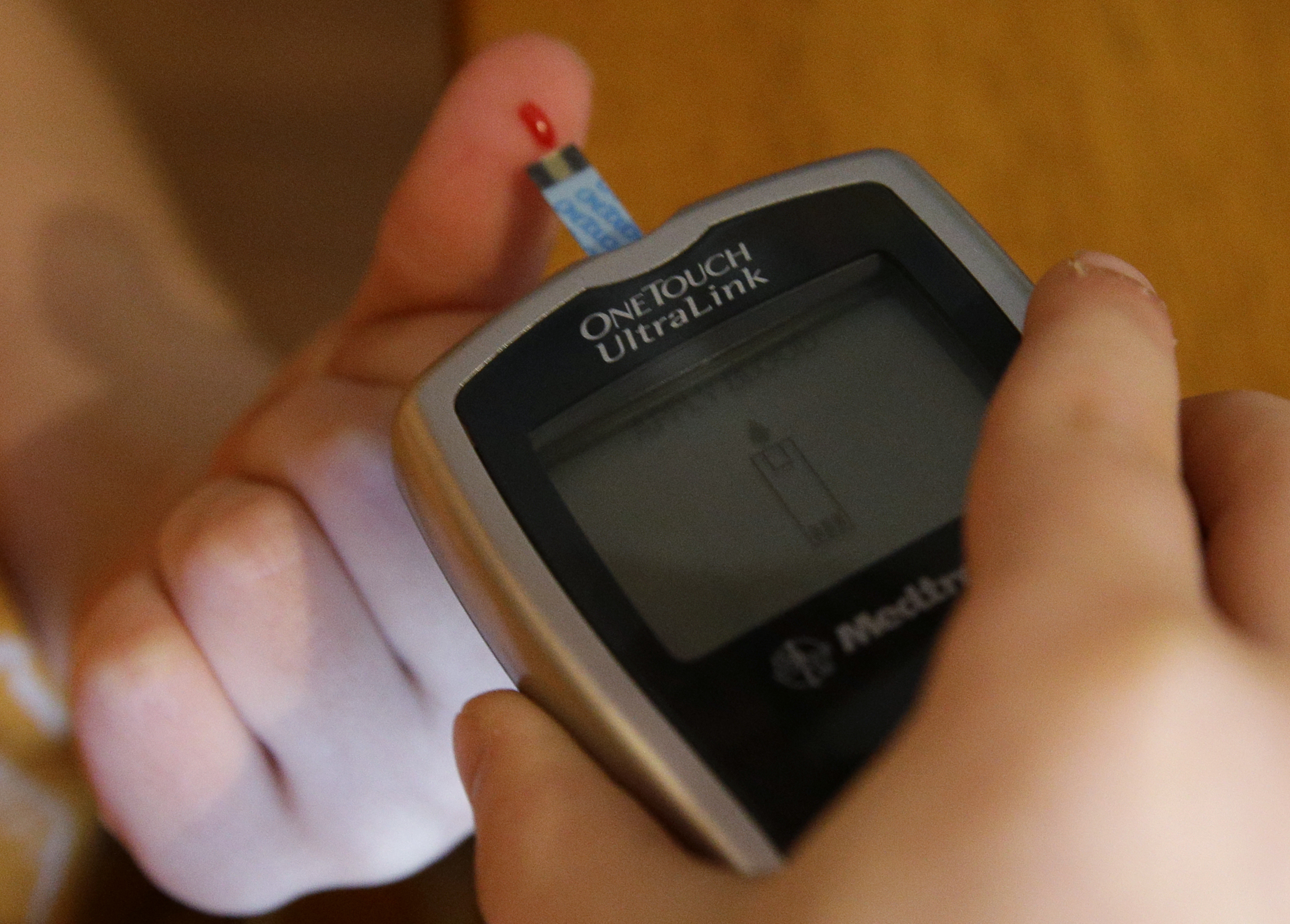 Boy with Type 1 diabetes pricks finger to test blood sugar levels