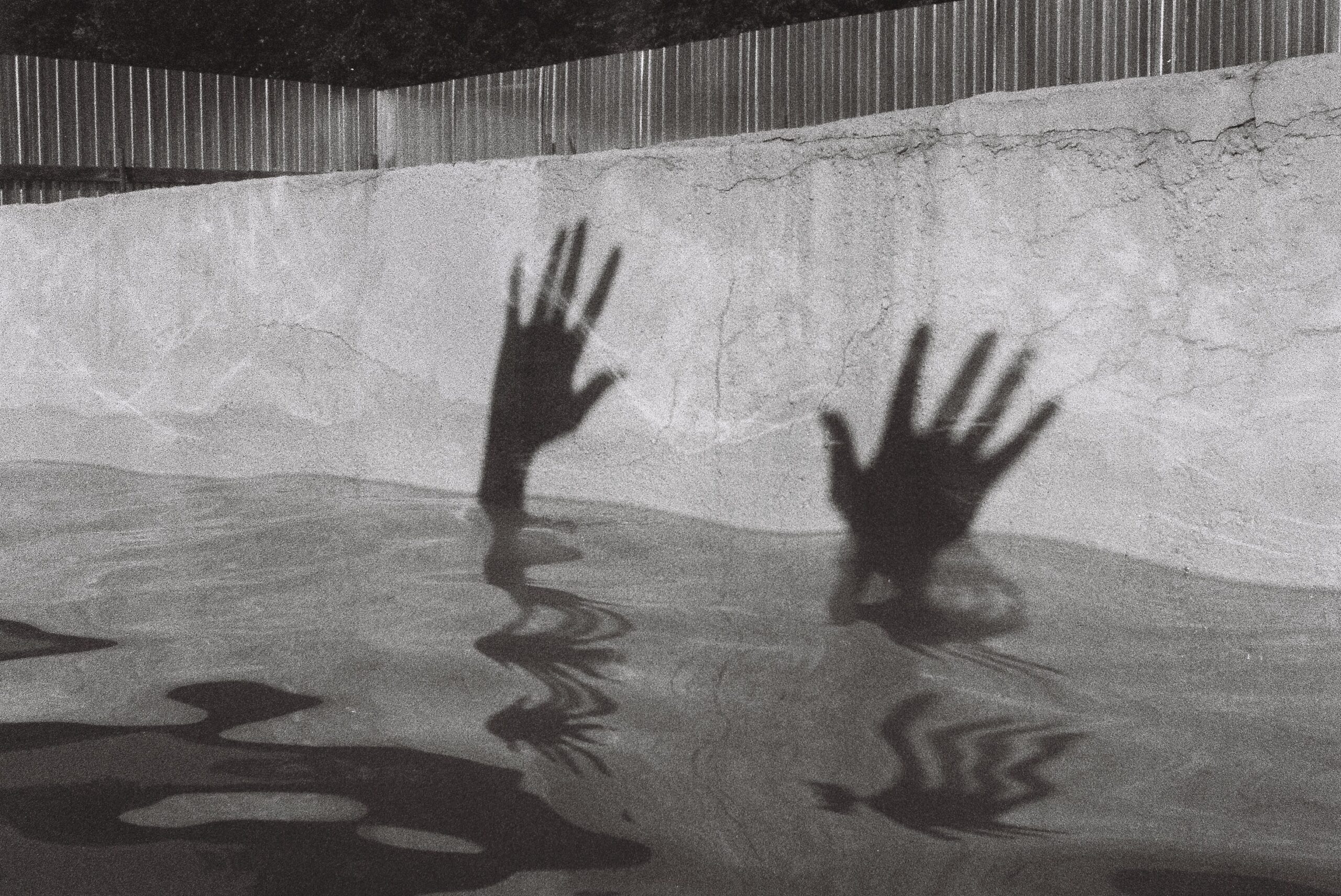 The shadow of two hands rising out of a pool