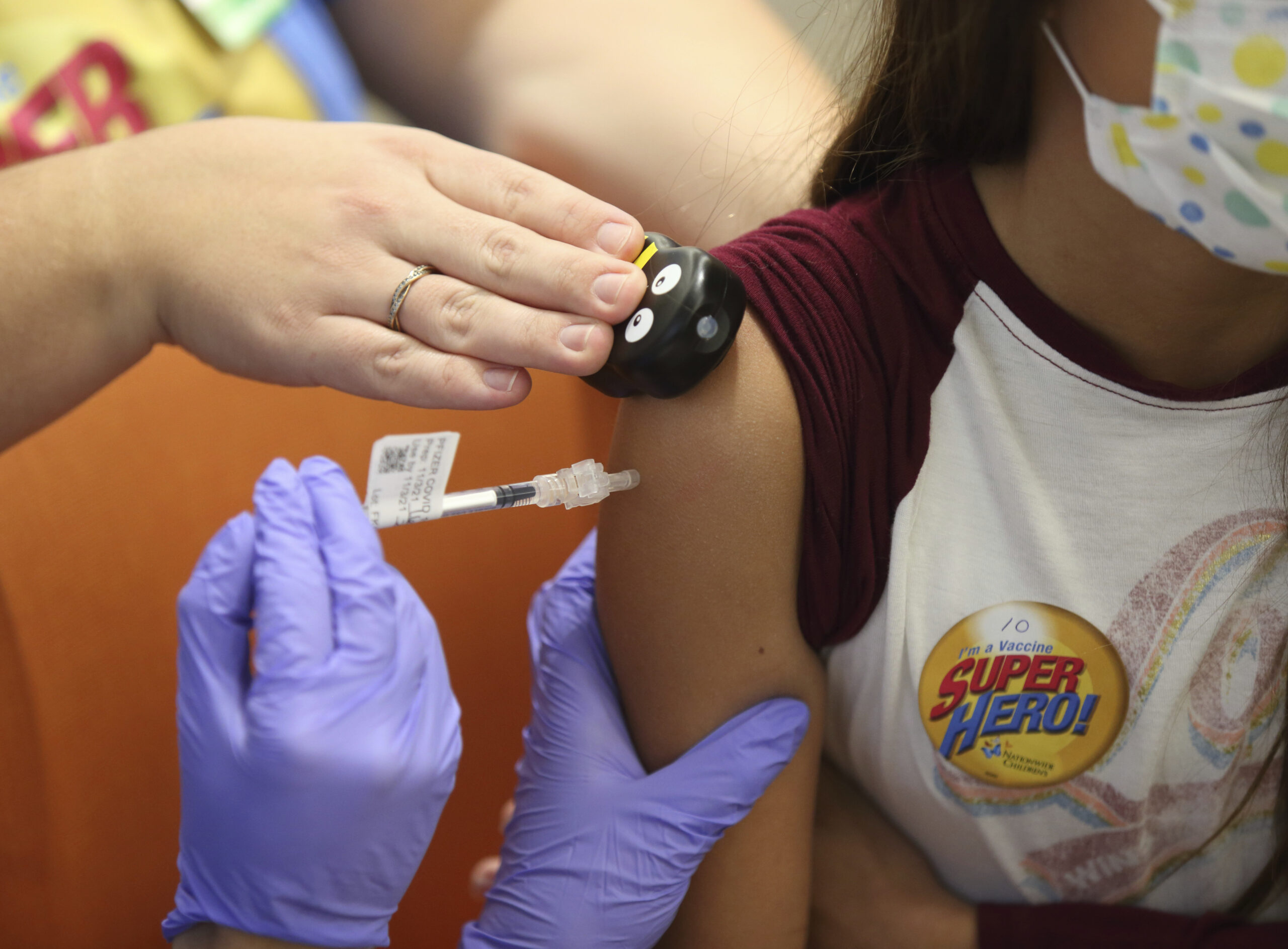 Parker McKenzie, 10, right, receives a Pfizer COVID-19 vaccine
