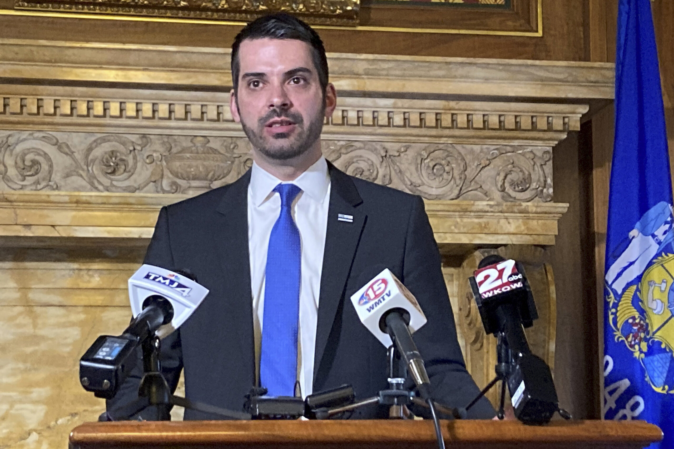 Fond du Lac County District Attorney Eric Toney stands at a podium with microphones on the stand