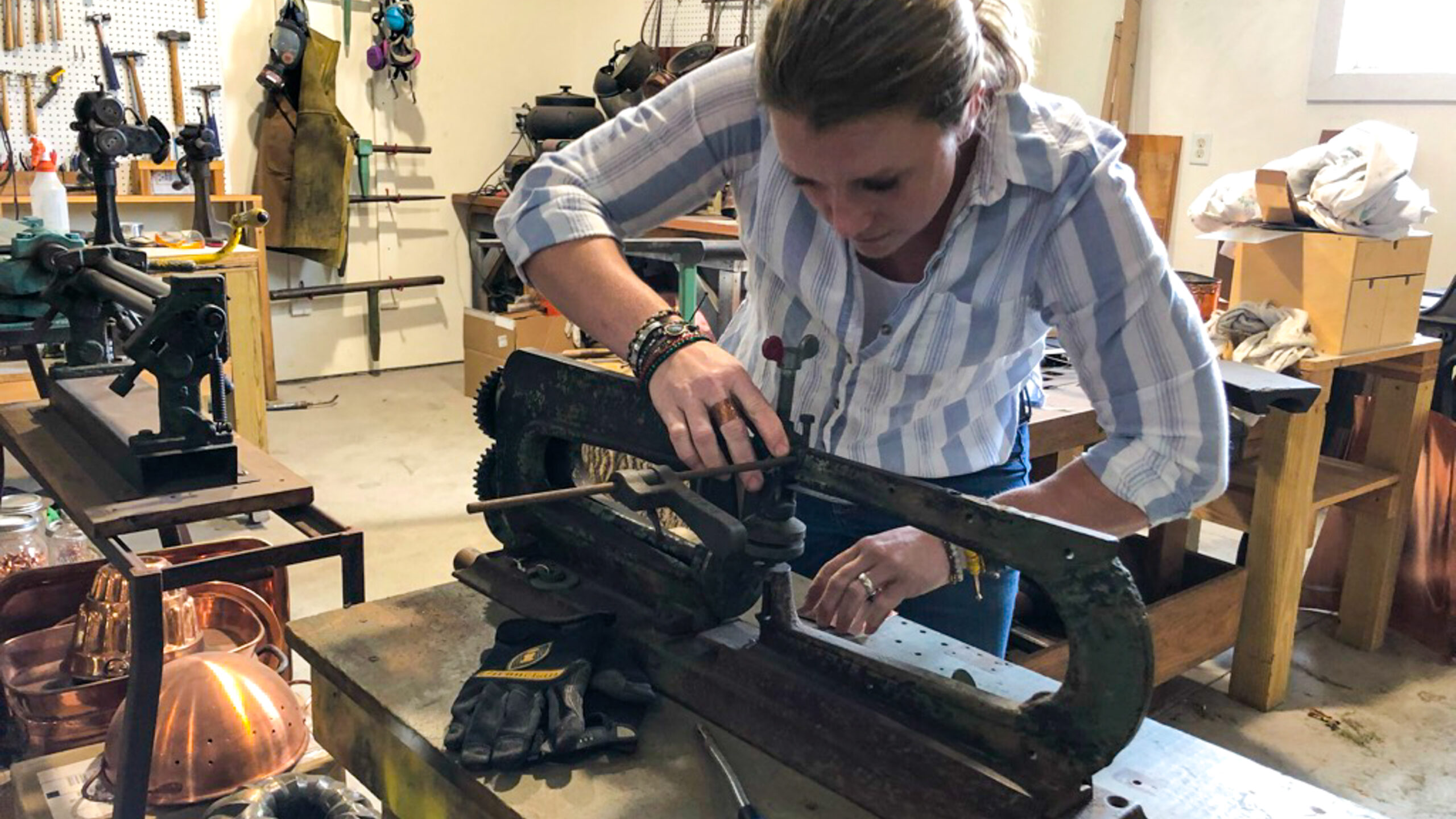 Sara Dahmen working in her shop to shape a copper mug.