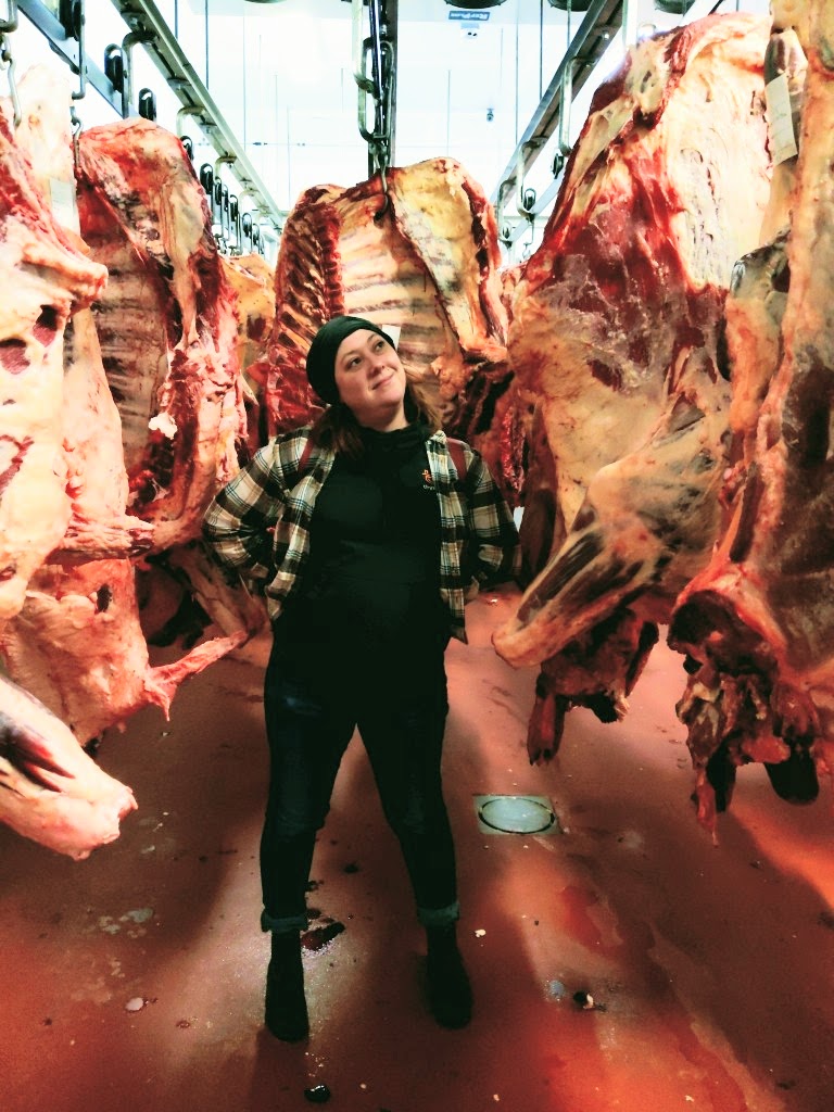 Heather Oppor stands surrounded by carcasses of meat