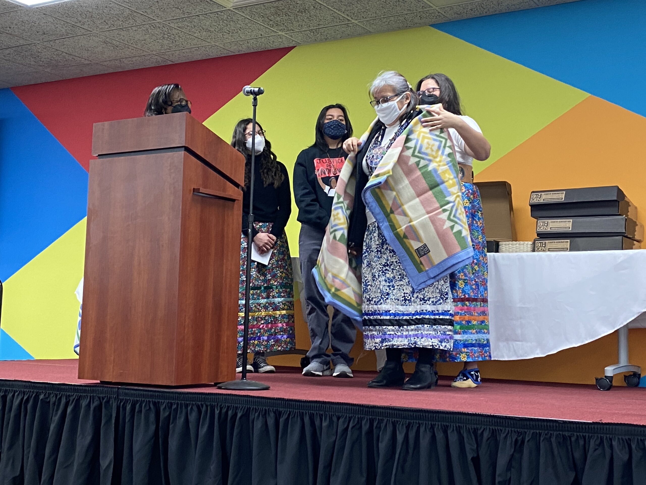 Madison School District's Shaya Schreiber, alongside student leaders Marena Fox Baker and Isa Saiz, presents Tara Tindall with a blanket at Monday's land acknowledgement ceremony