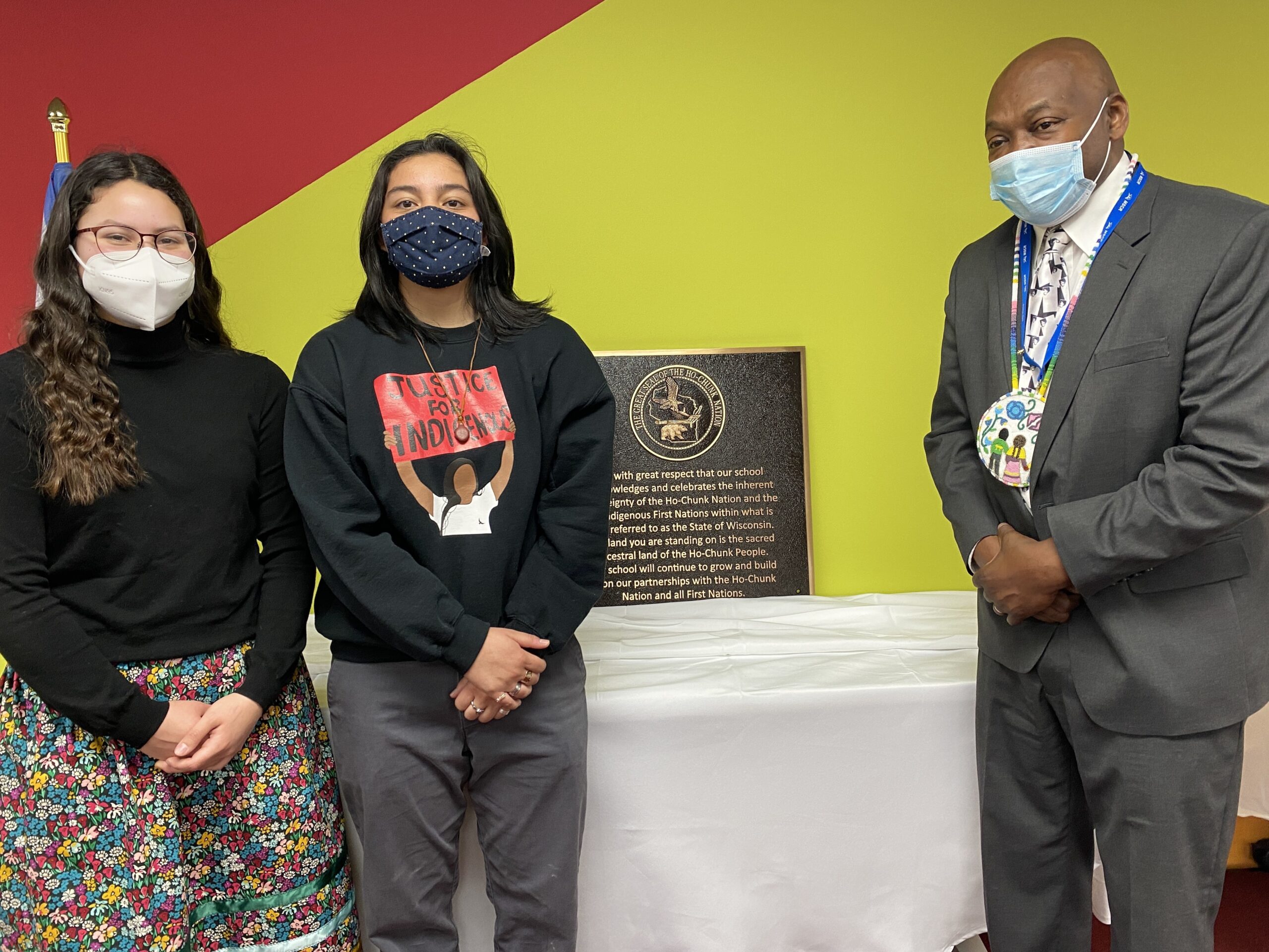 Two students stand with District Superintendent Carlton Jenkins with the land acknowledgement plaque