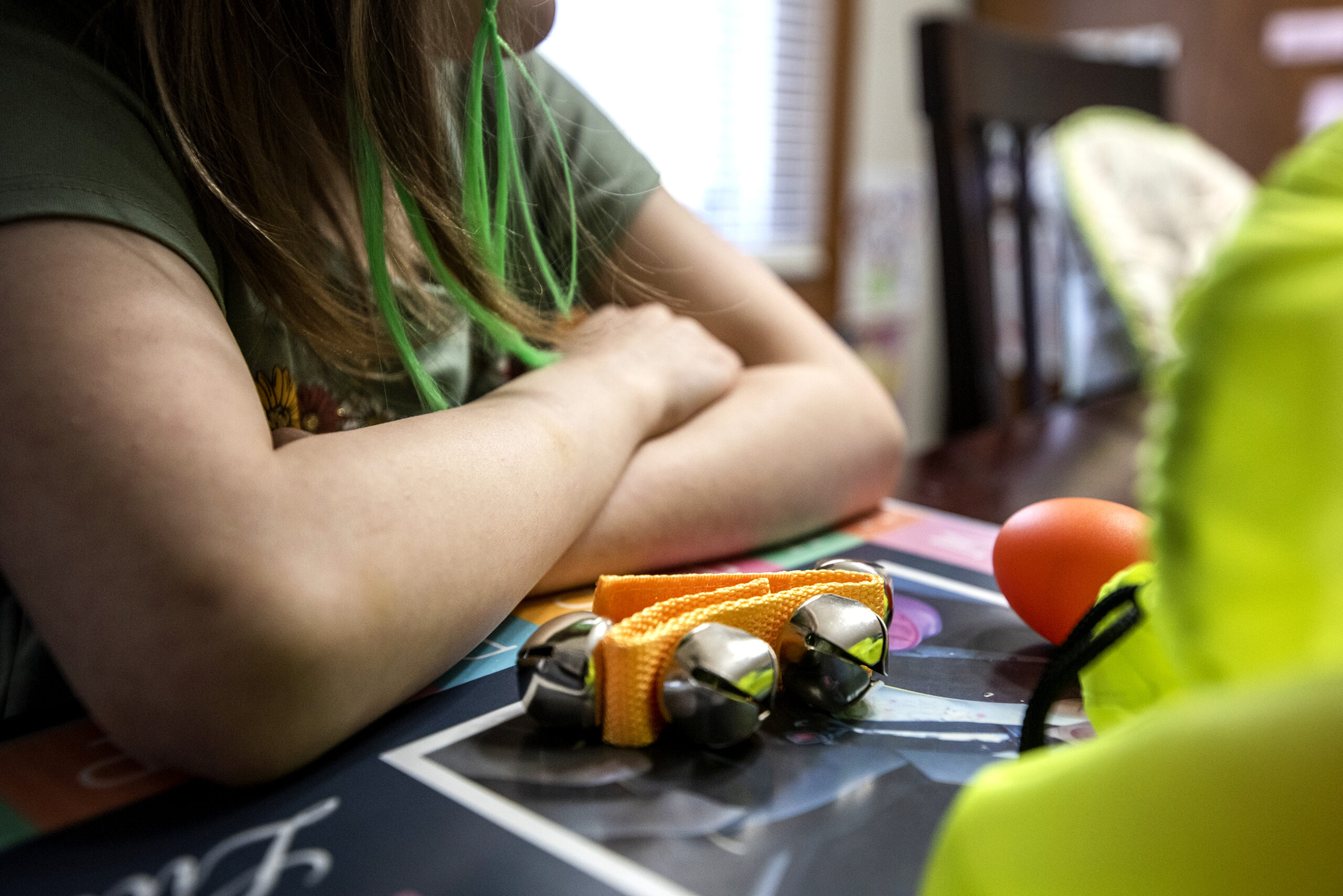 Bells sit in front of the student's crossed arms as she sits in front of her laptop.