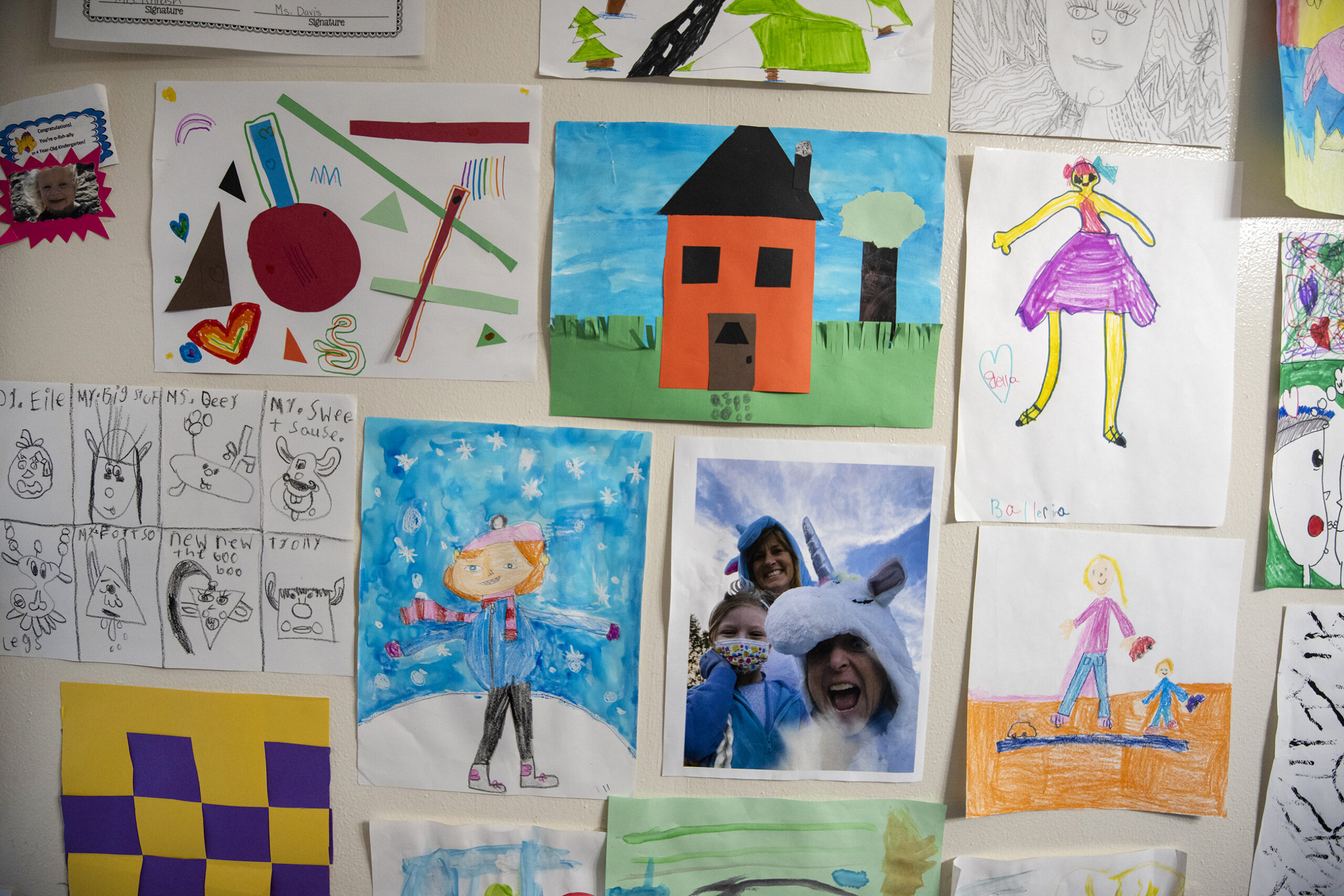 Colorful drawings and photographs are displayed on a wall.