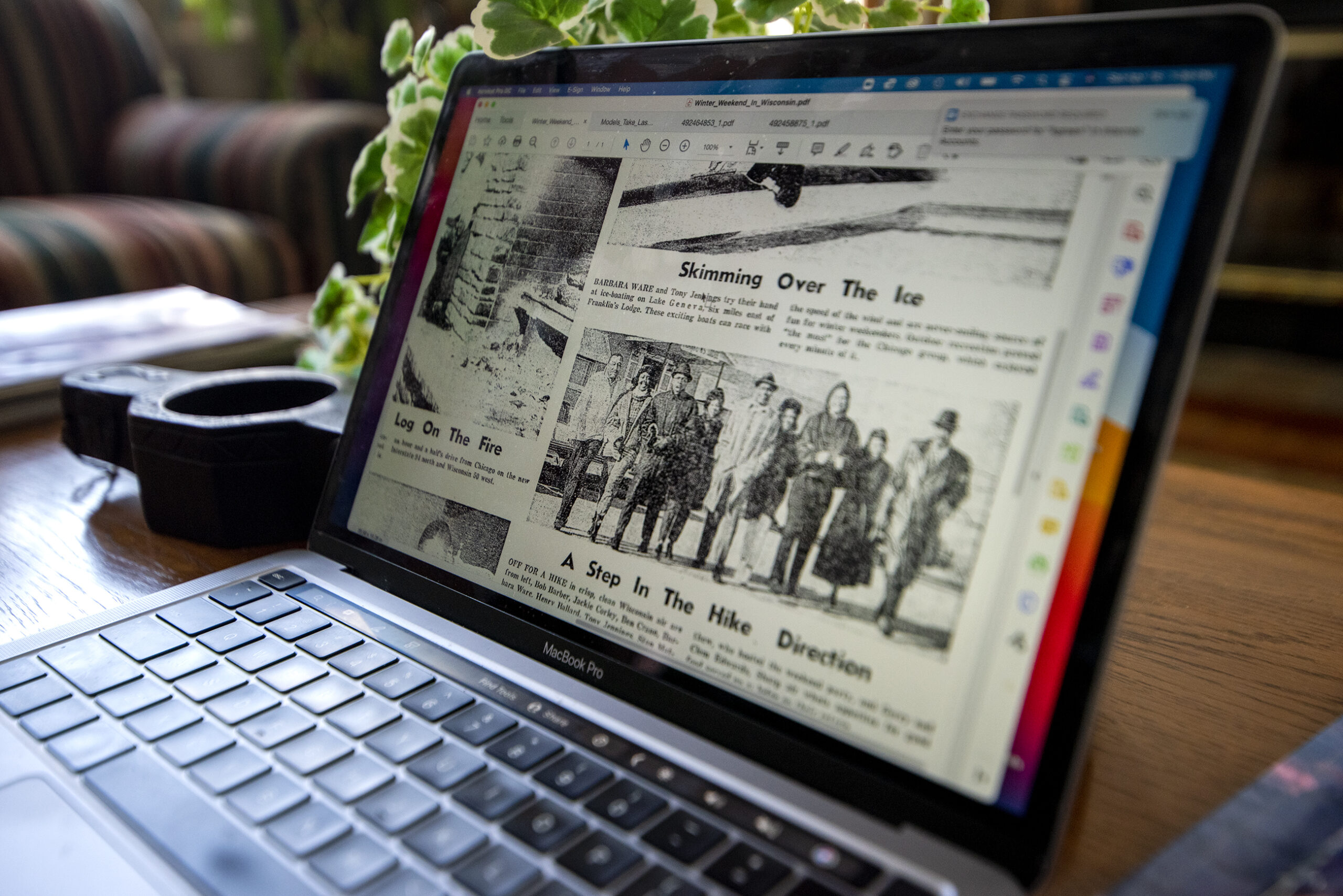 Black and white photographs from a newspaper are seen on a laptop screen.