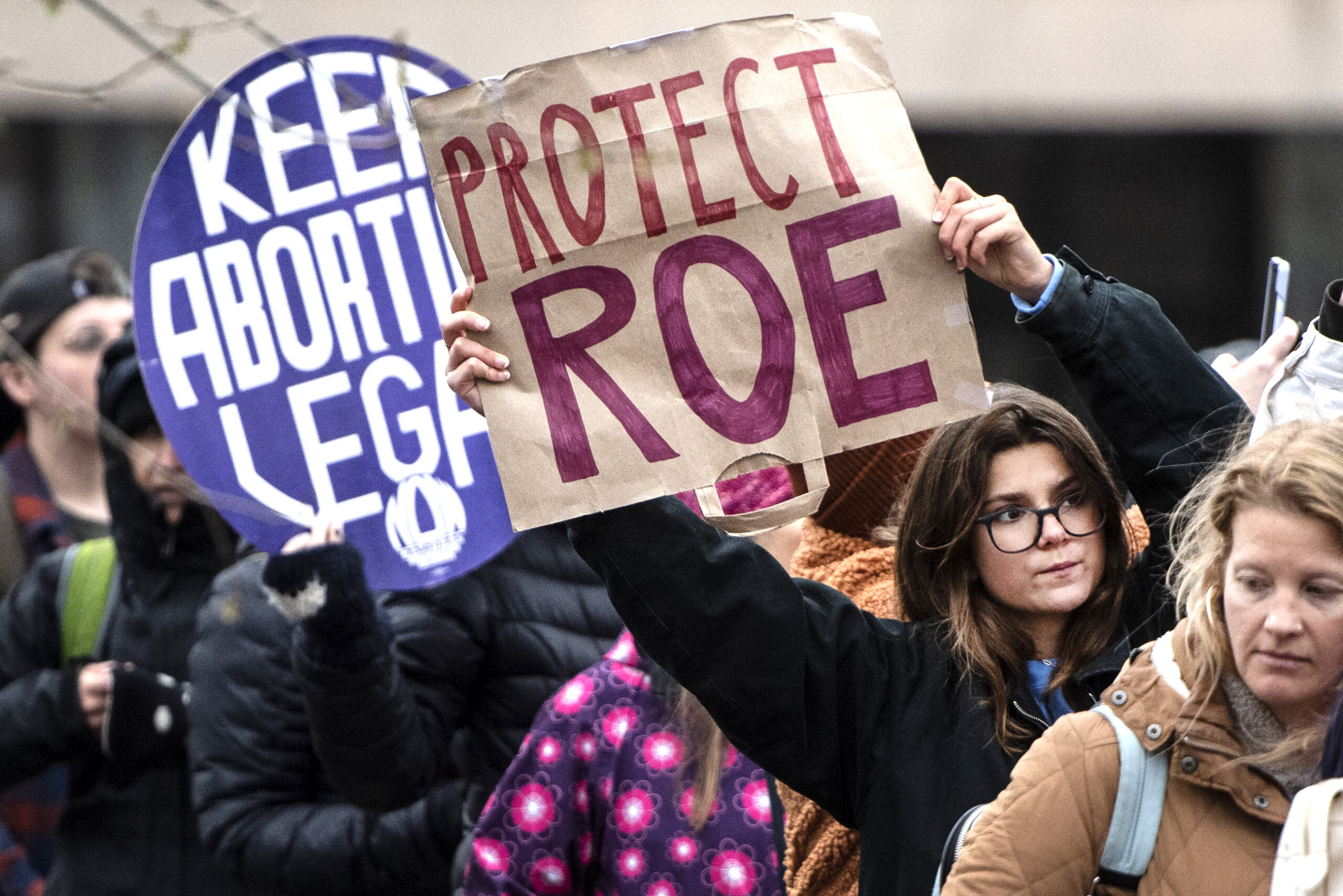 Protester's signs say "Protect Roe" and "Keep Abortion Legal."