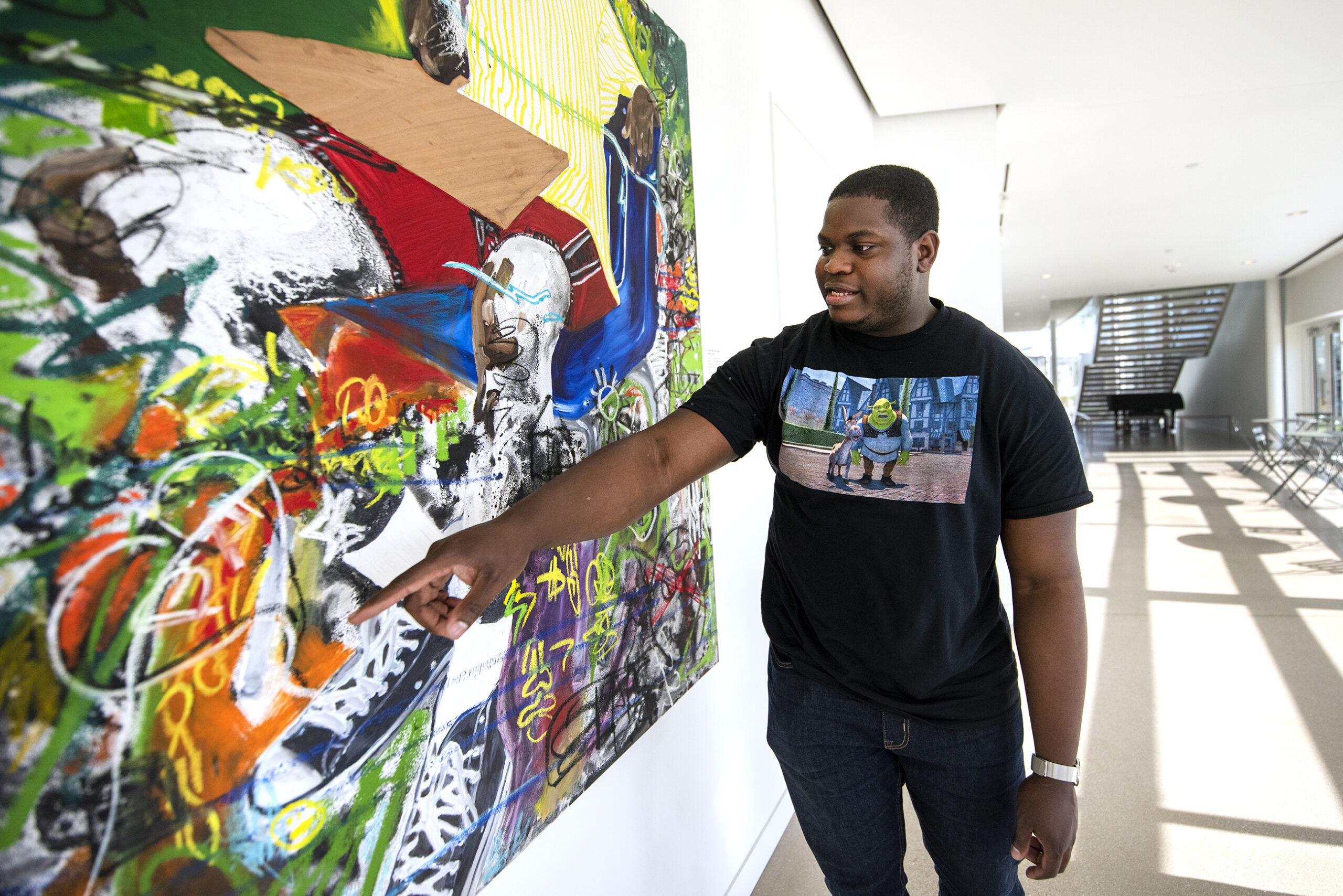Khari Turner points to colorful details, many layered on top of the other, during a tour.
