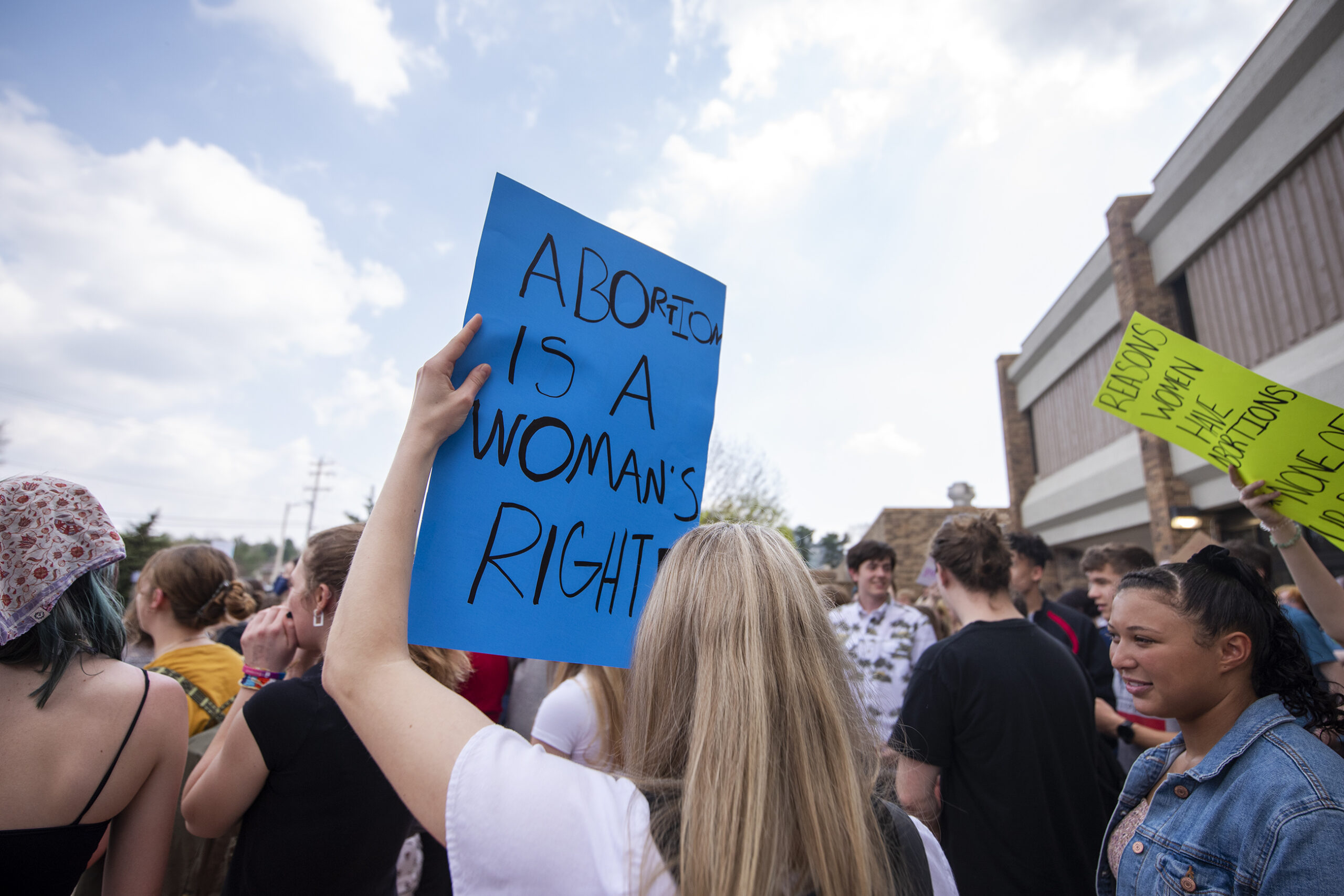 A blue sign that says "abortion is a woman's right" is held by a student.