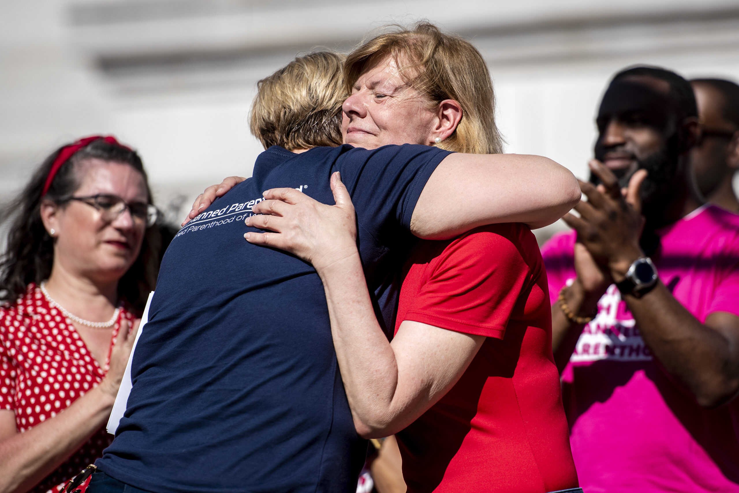 Tammy Baldwin smiles as she hugs Tanya Atkinson at an outdoor rally.