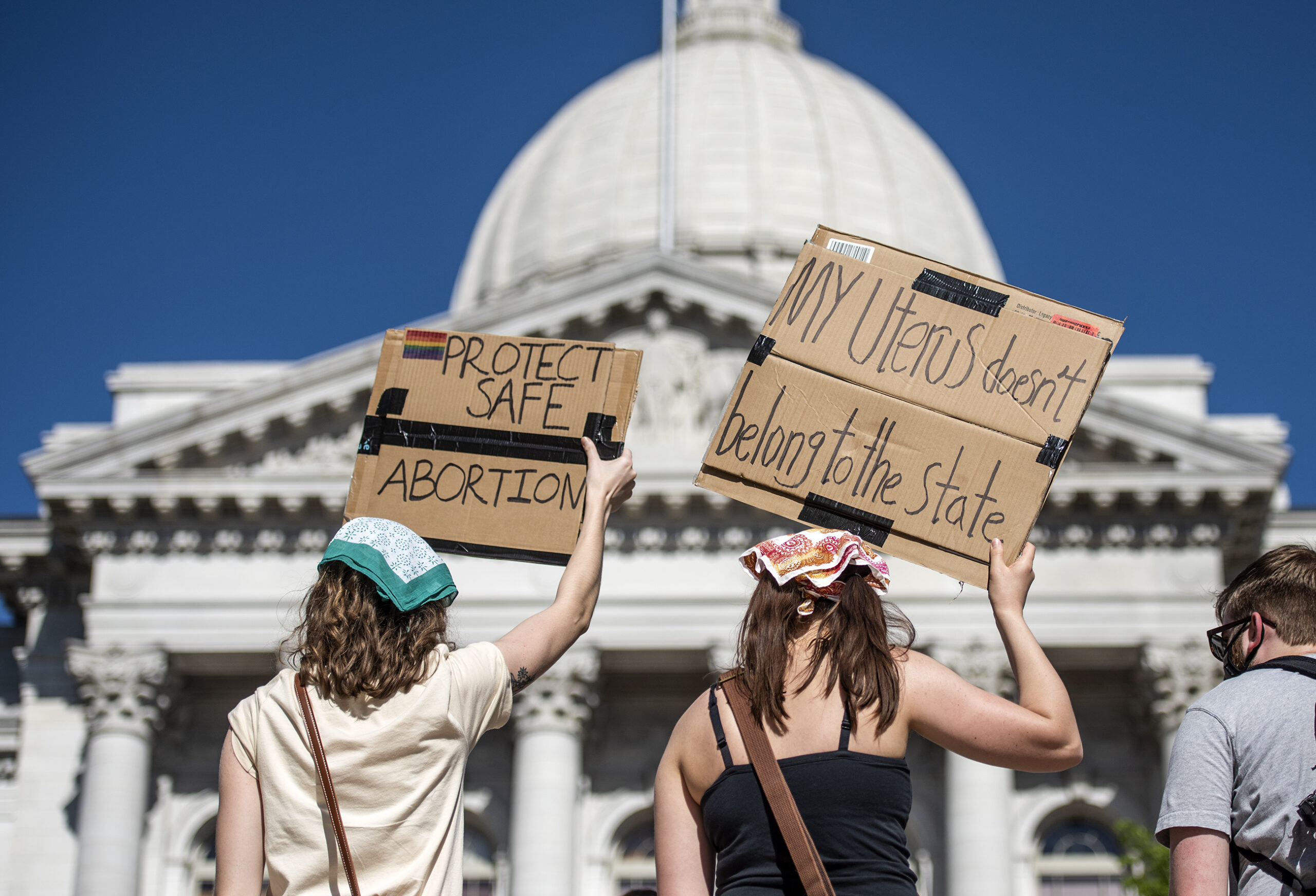 The white dome of the Wisconsin state Capitol can be seen behind two signs in support of abortion access.
