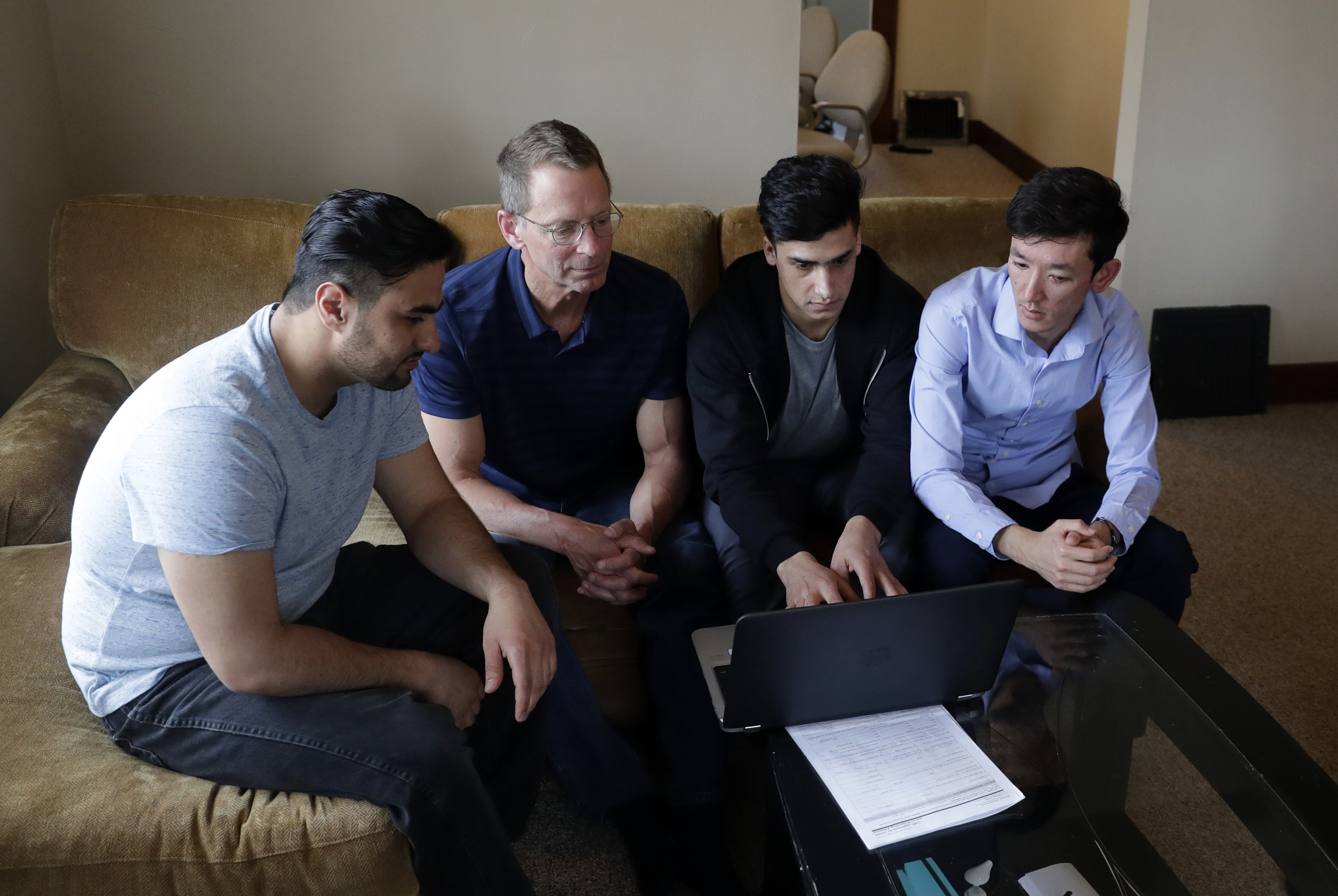 Mike Ruminski, helps Muddassir Saboory, Fayaz Nabizada and Ali Akbar Gholami work on the computer
