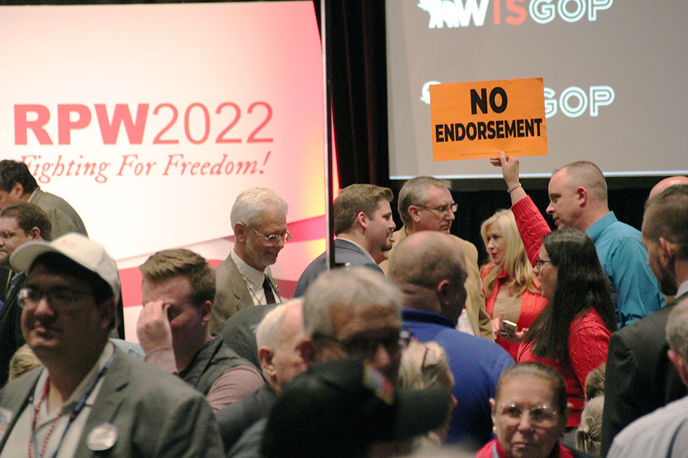 A woman holds up a "NO ENDORSEMENT" sign at the 2022 Wisconsin Republican Party Convention.