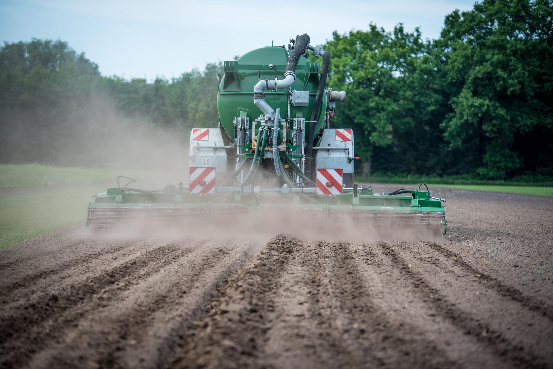 Spreading fertilizer on a field with a tractor.