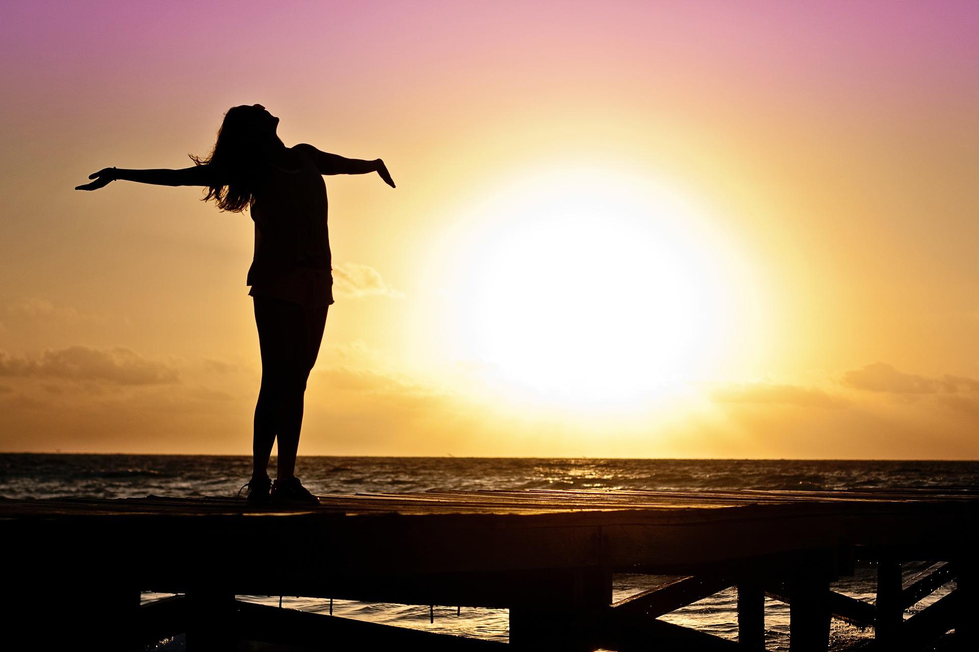 Women standing on dock as sun comes up.