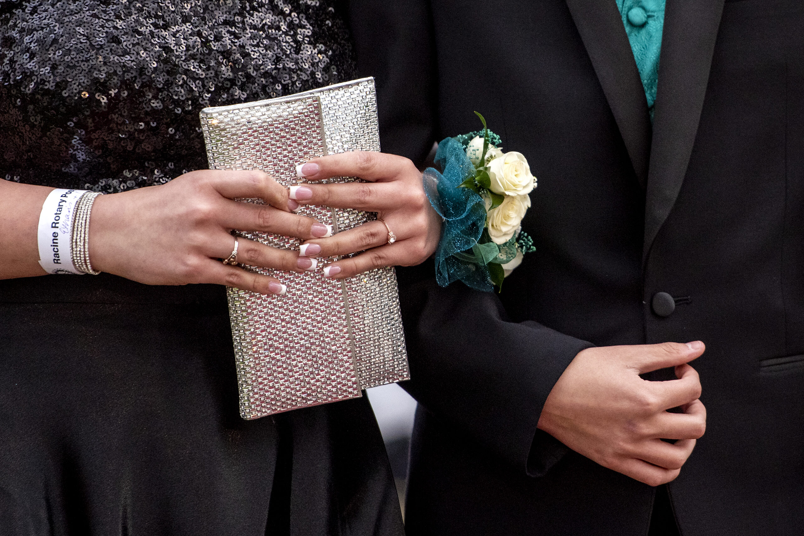 Details showing two prom dates with a glittery clutch bag, a corsage with white flowers, and formal wear.