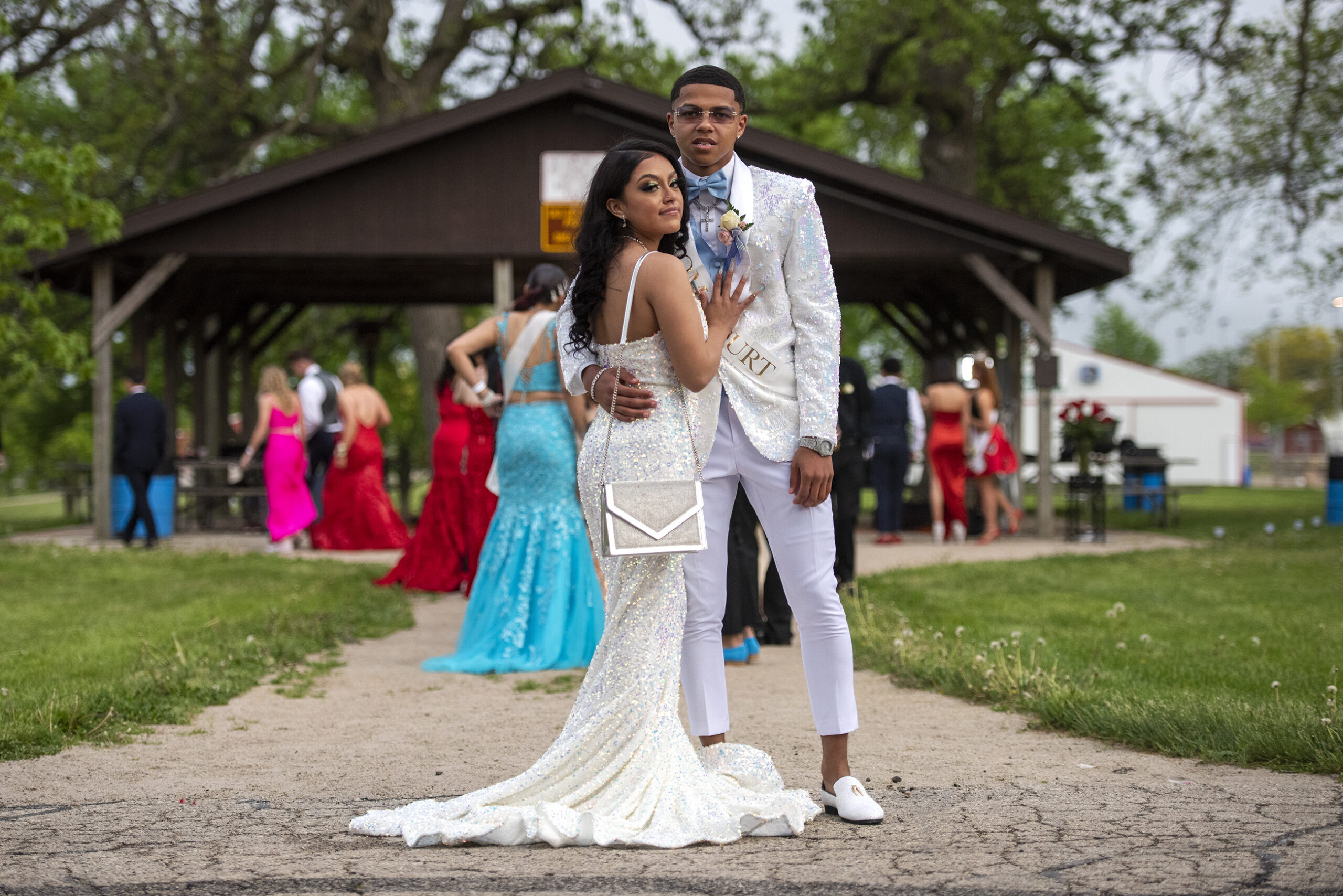 A couple of attendees wear all white as they pose together outside at the fairgrounds.