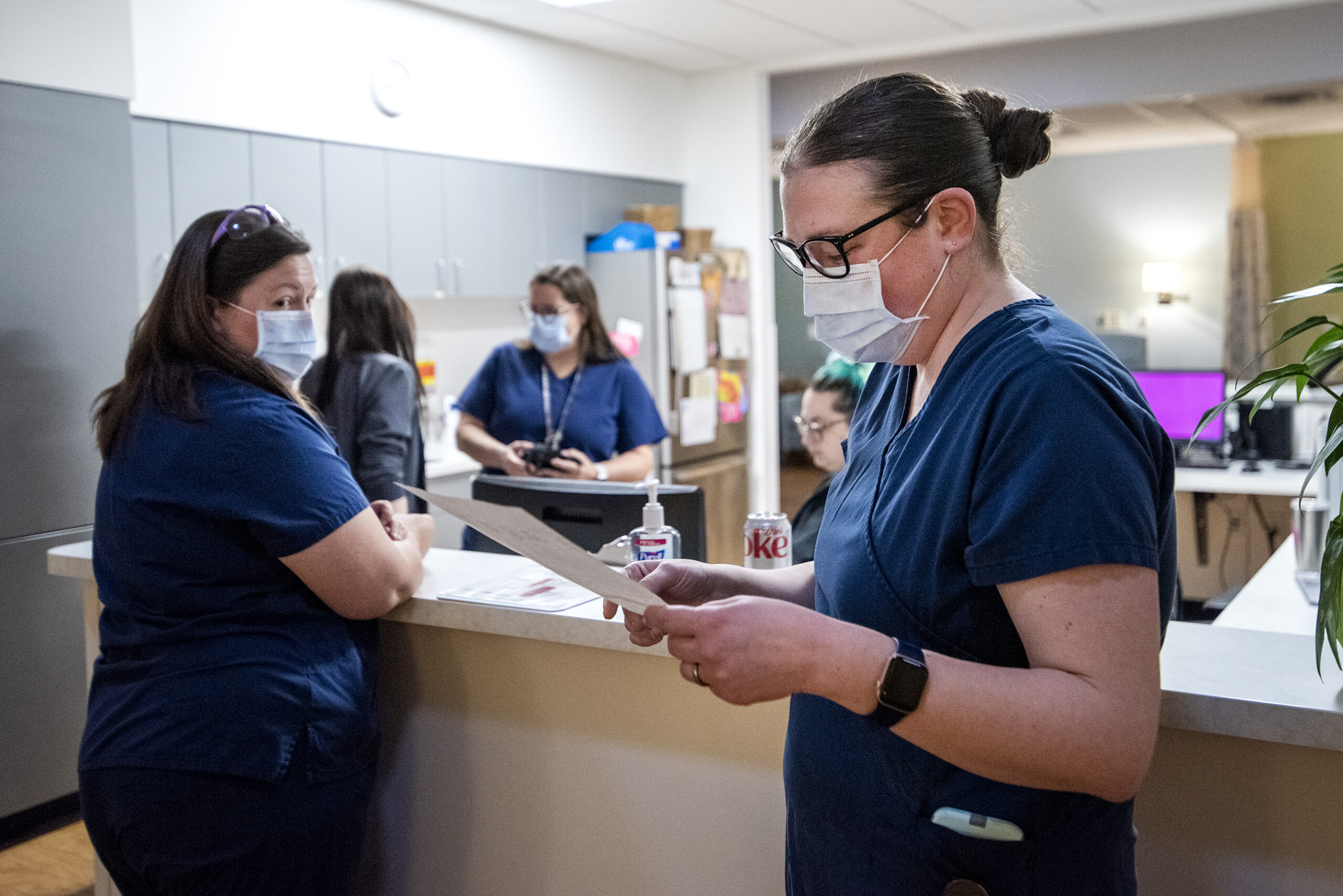 A nurse reads from a list as other nurses nearby listen.