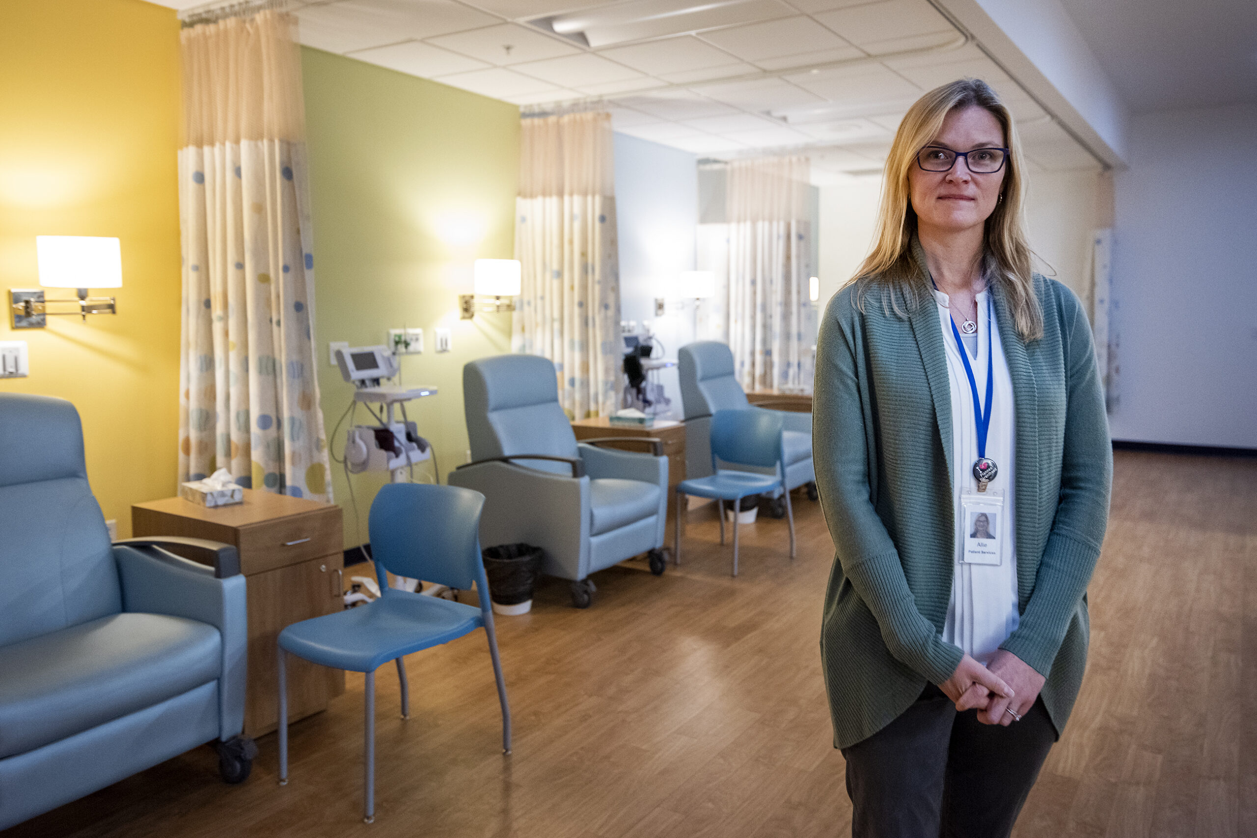 A doctor stands in the recovery area which has cushioned seats and privacy curtains.