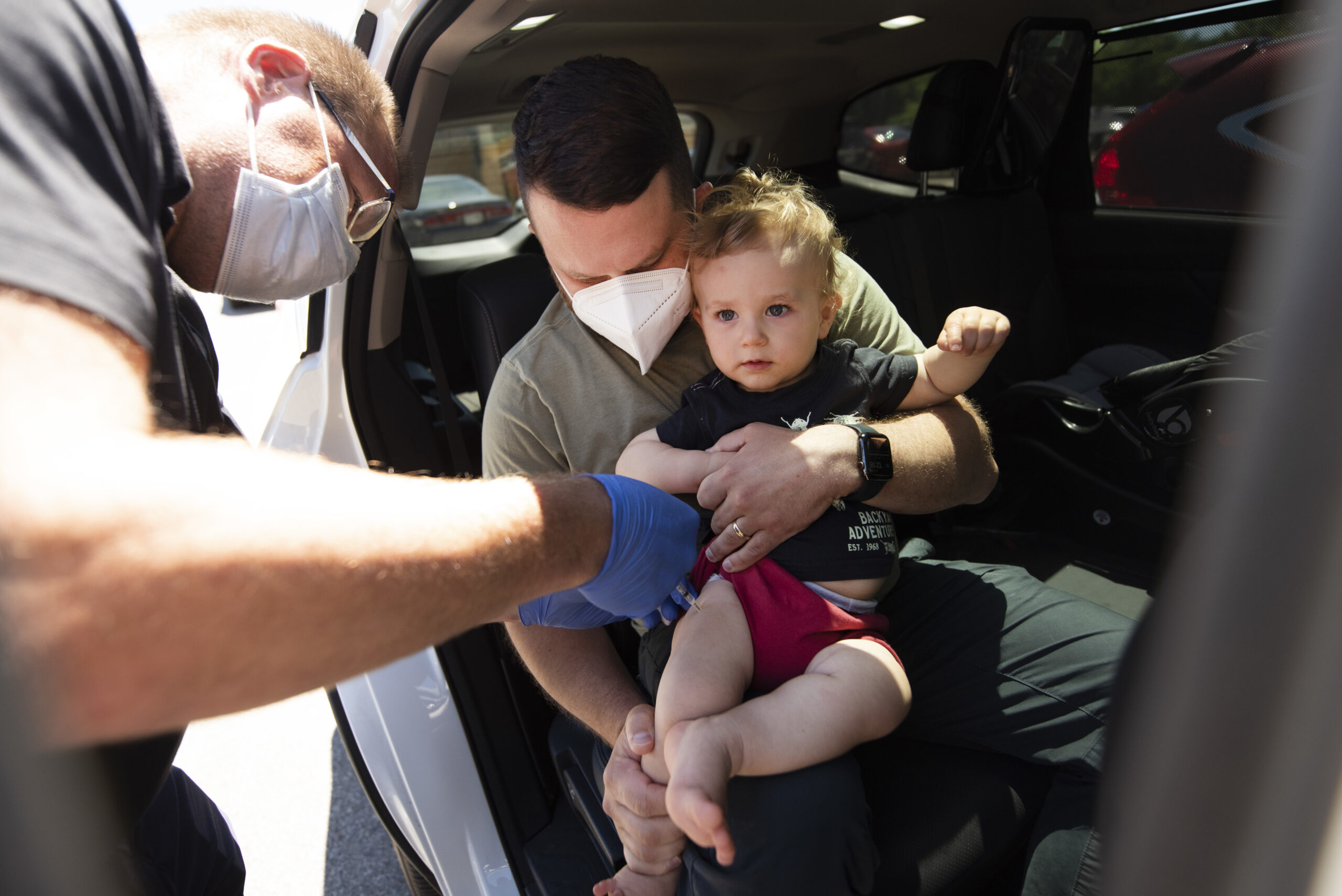 A father holds his young son as he receives a shot in his leg.