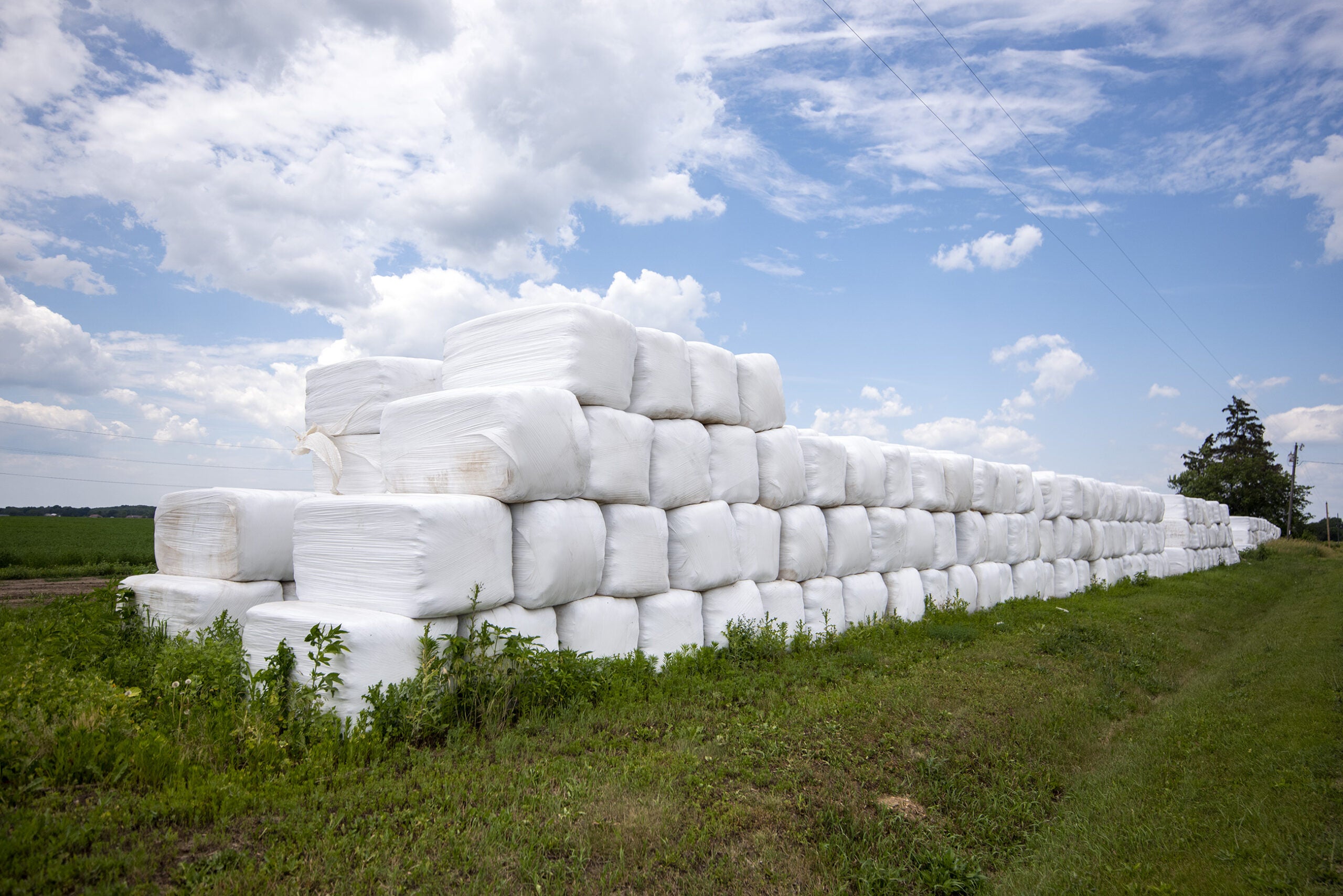 Plastic is wrapped in a rectangular shape around material on a farm.