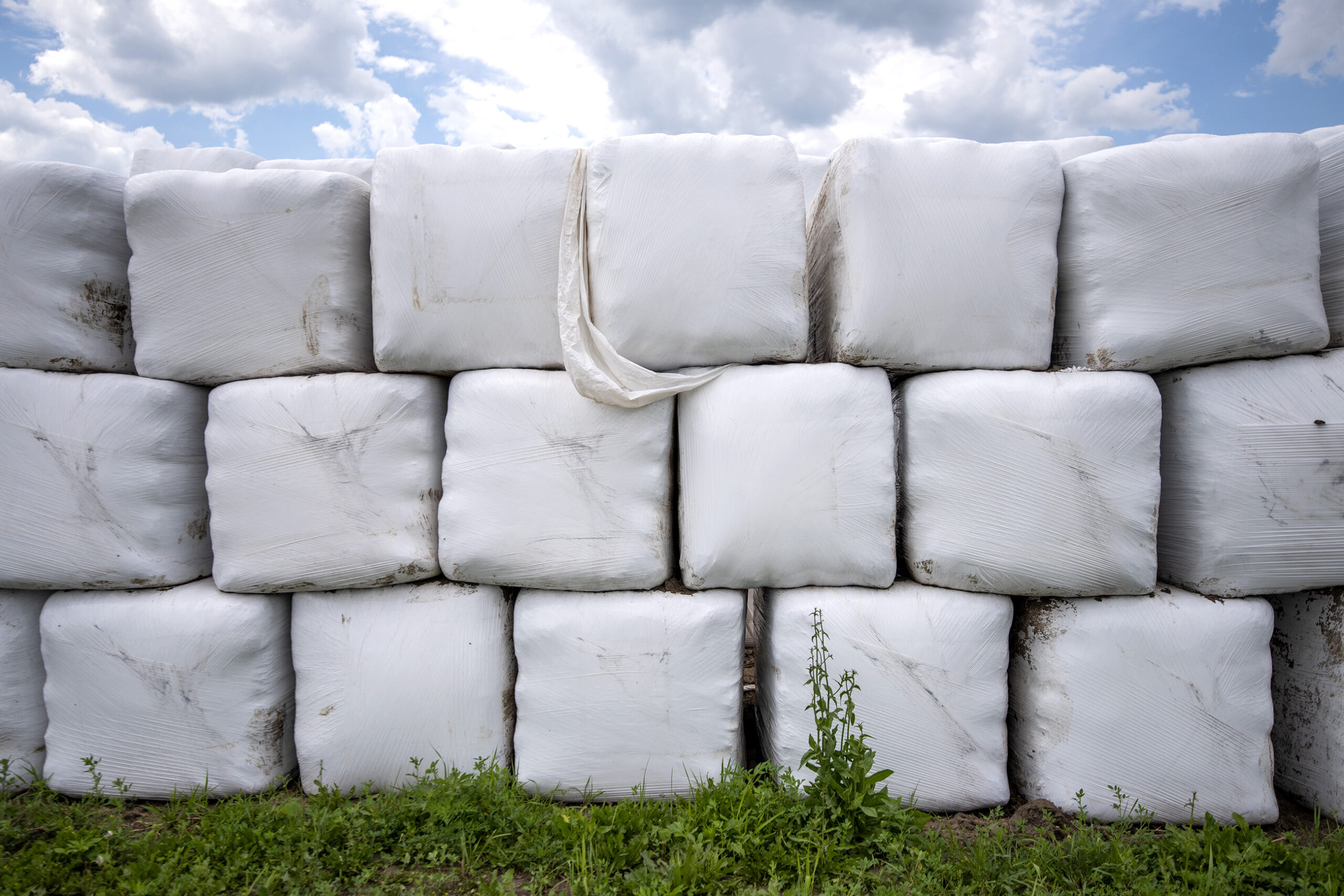 Plastic-wrapped supplies are stacked up on a farm.