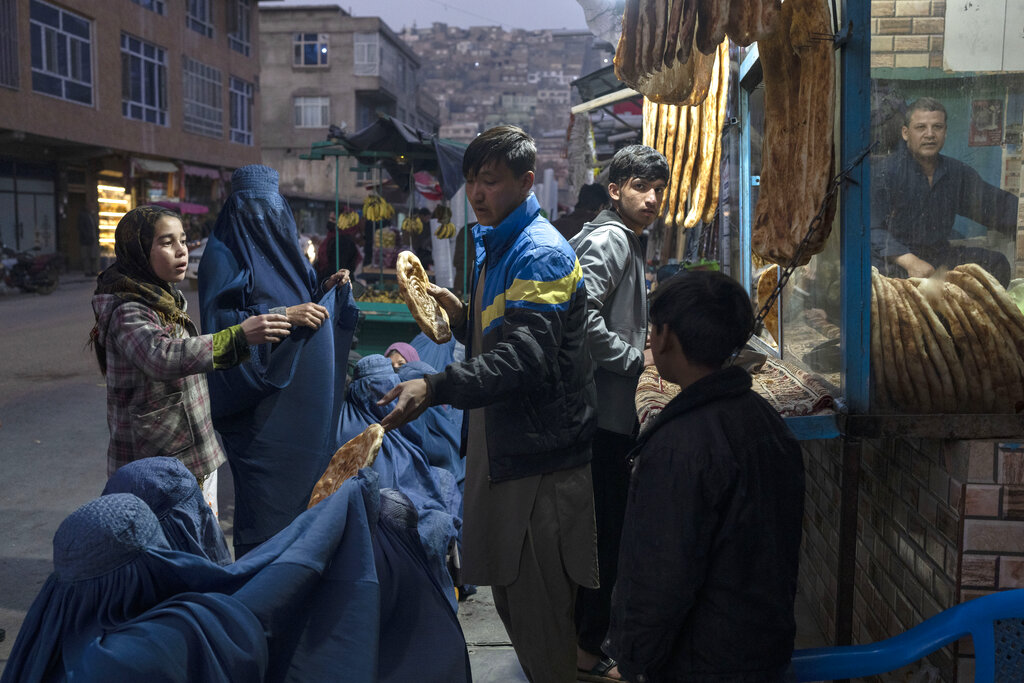 A man distributes bread to women outside a bakery in Kabul, Afghanistan.