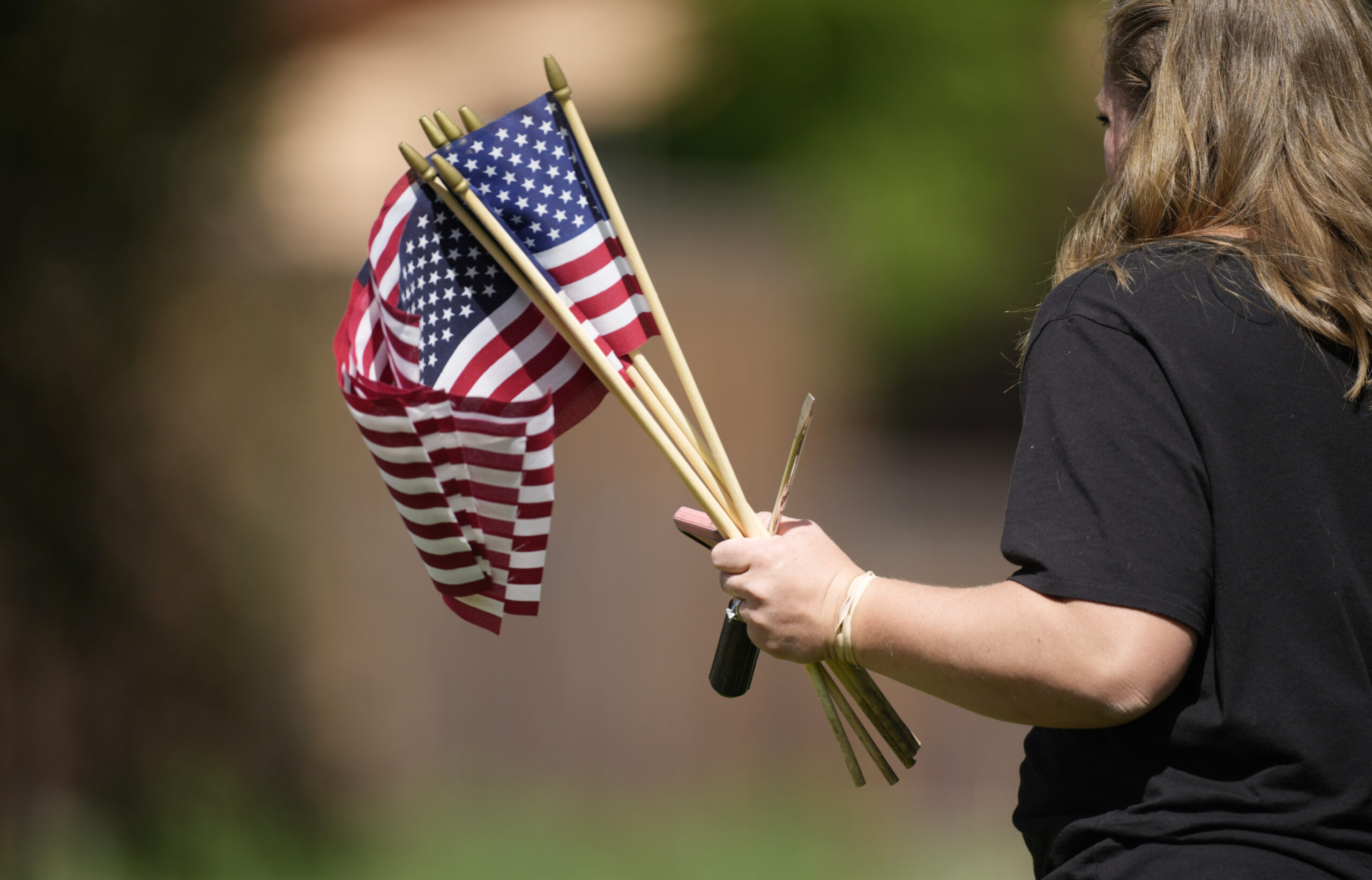 A volunteer holds a bundle of American flags at Fort Logan National Cemetery.