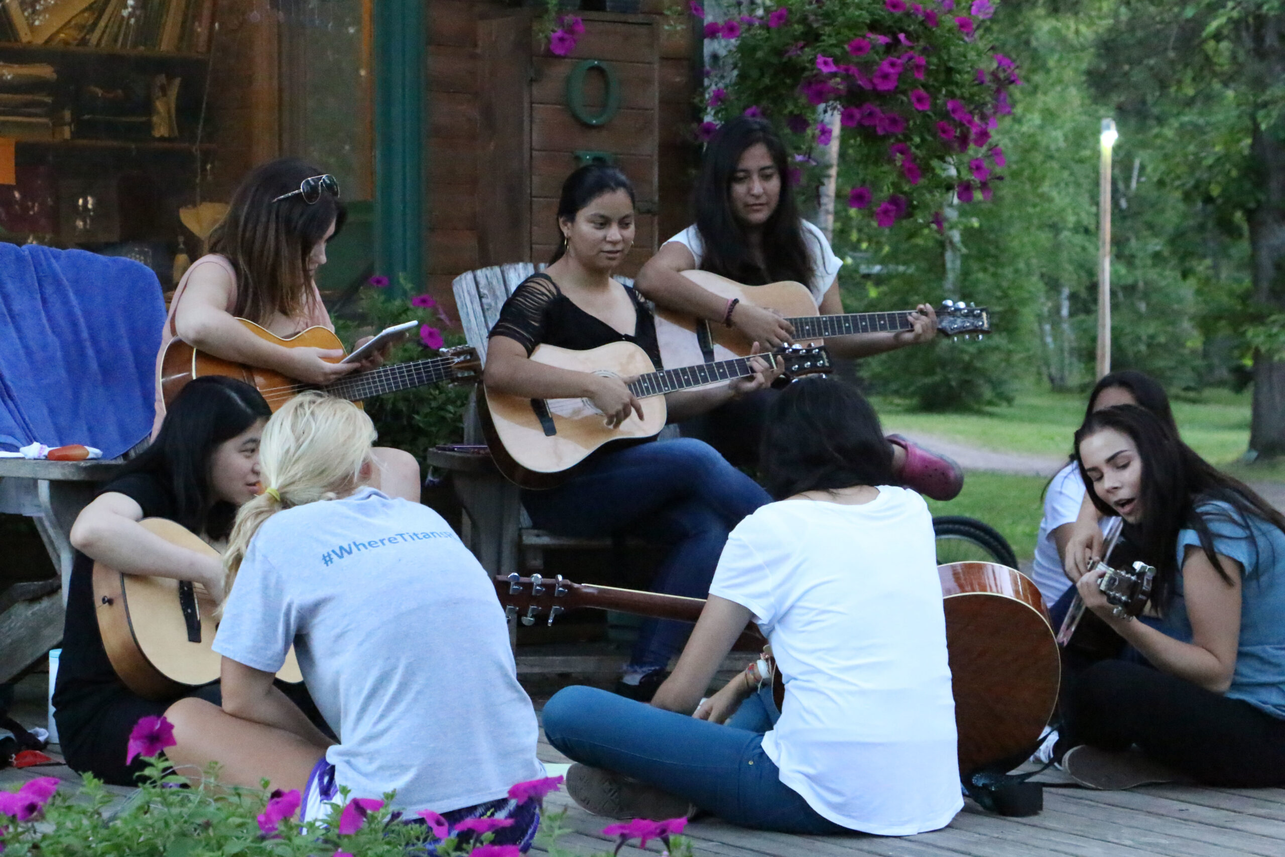 People sit as a group playing guitar and singing at Birch Trail Camp
