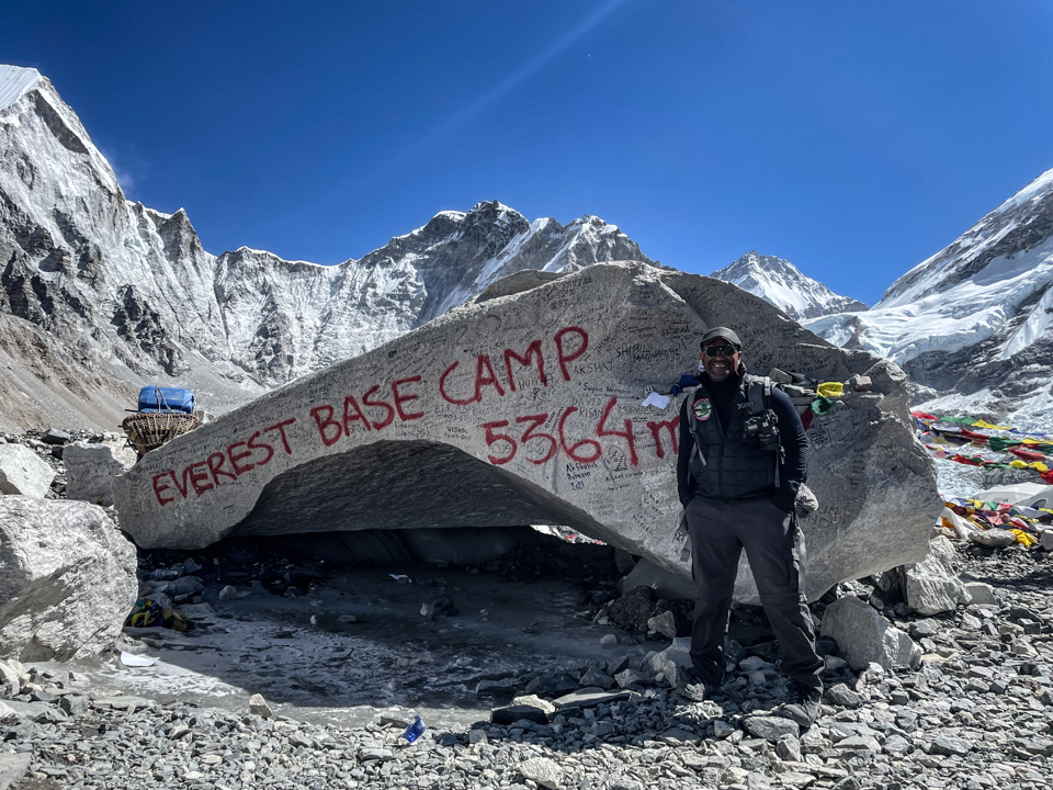 A man poses next to a rock structure at the base camp near Mount Everest
