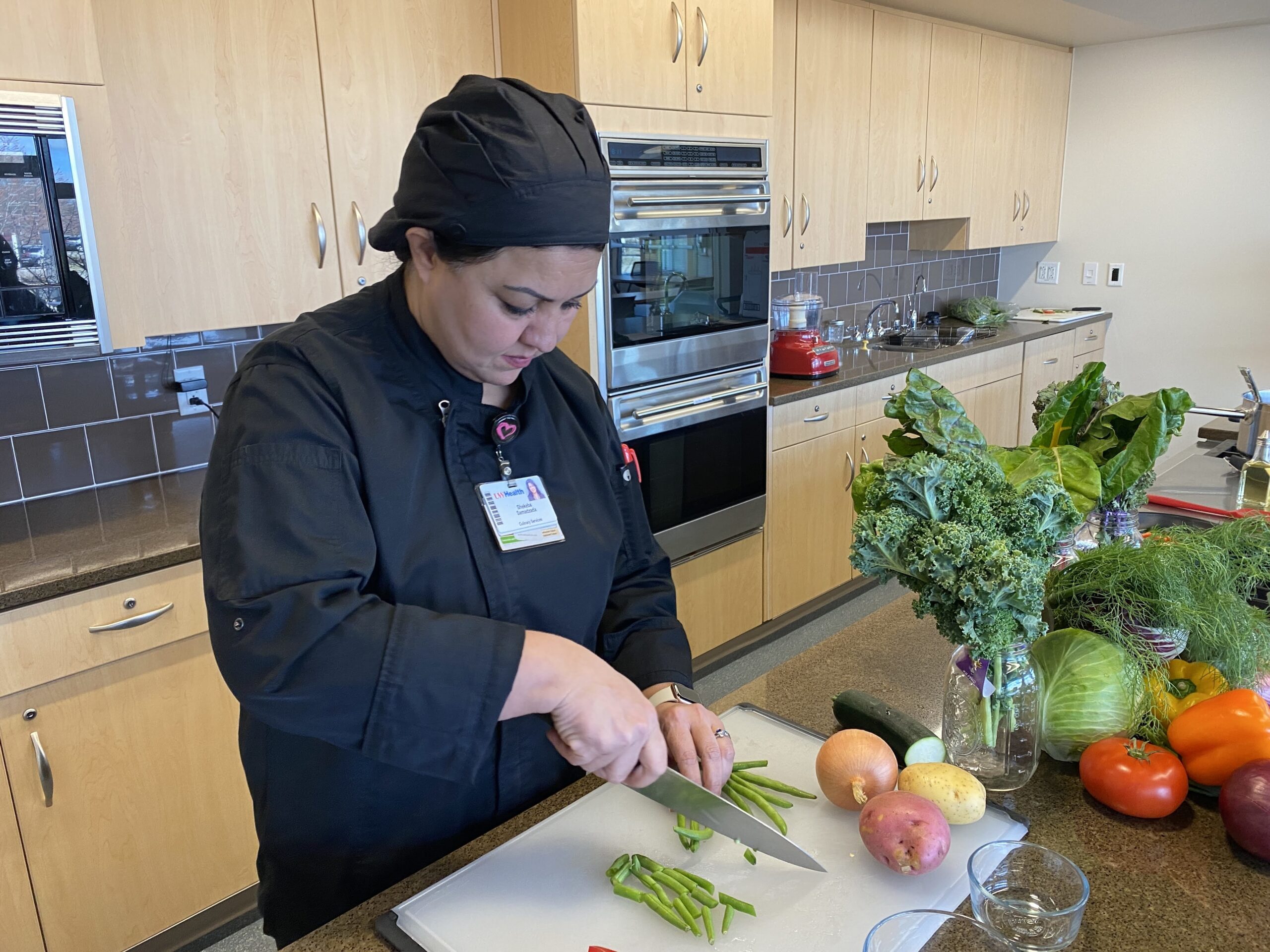 Shekeba Samadzada chops green beans in a kitchen at UW Hospital as she prepares a vegetable korma dish