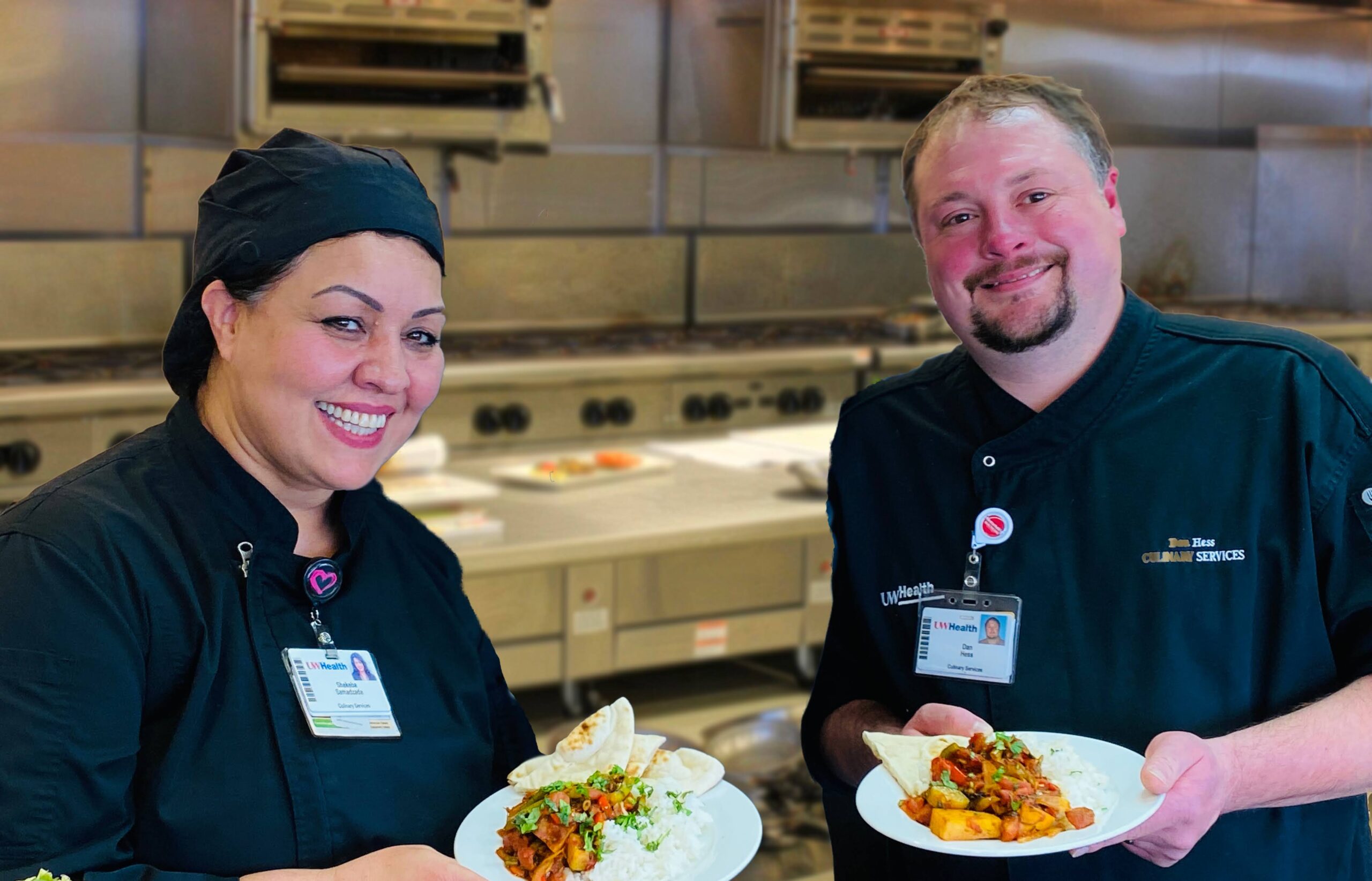 Two chefs, Shekeba Samadzada and Dan Hess, stand smiling and holding a dish at UW Hospital in Madison