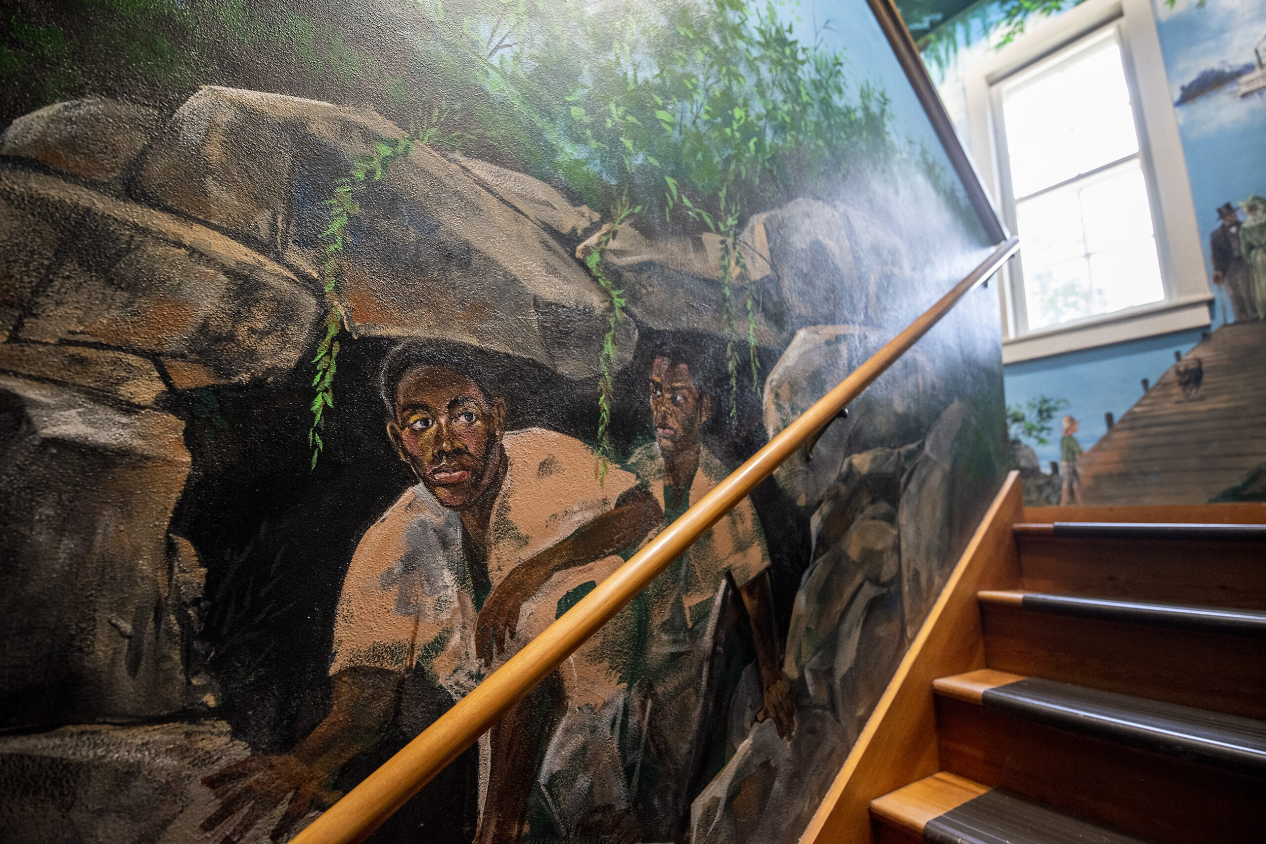 A wall mural depicts two men in a cave.